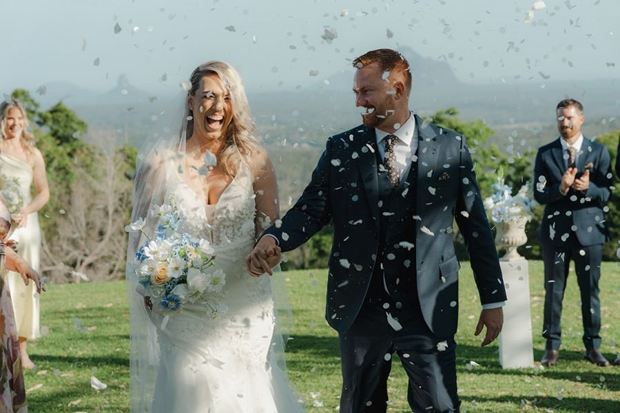 Newly married couple walks down the aisle through confetti exit at Maleny Orchard wedding venue