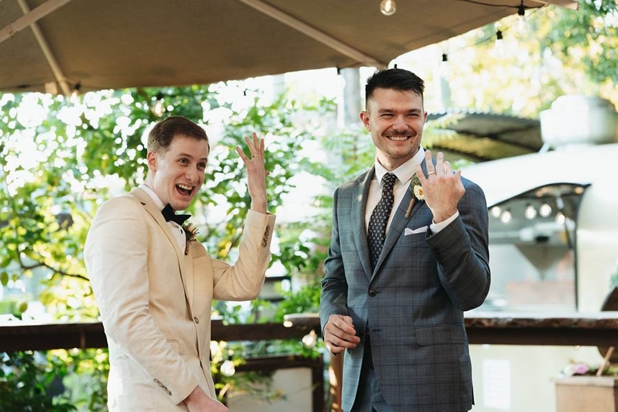 Happy grooms showing off their new rings at a Brisbane wedding