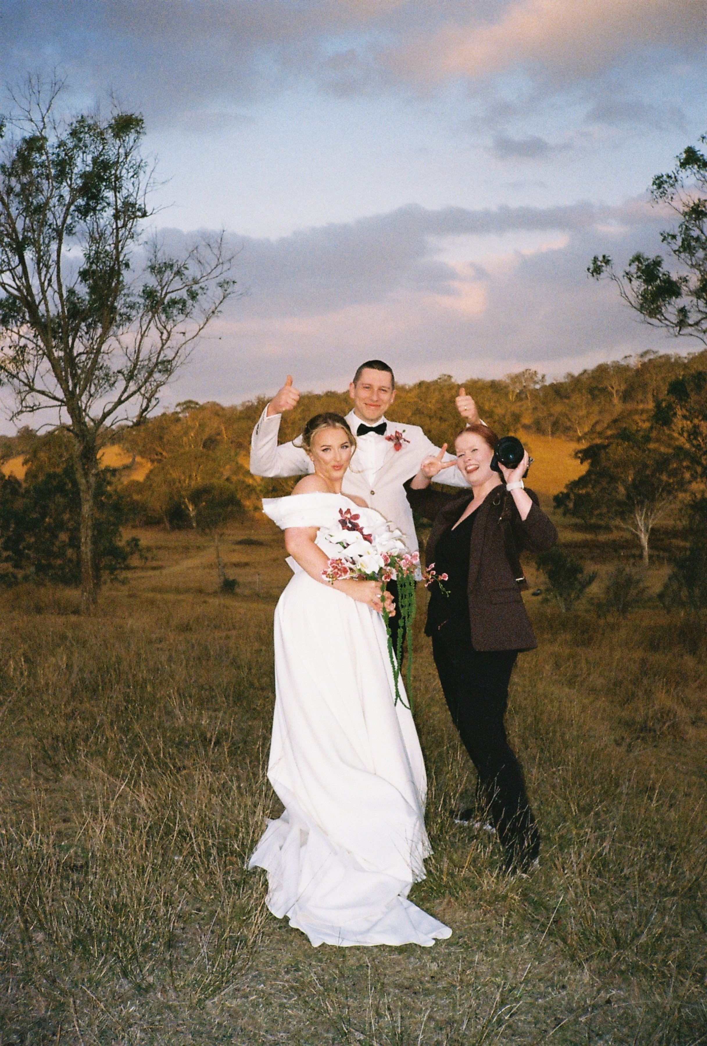 Bride & groom with their wedding photographer at golden hour