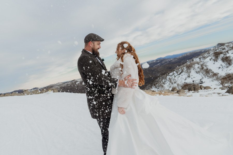 Bride and groom having a snowball fight on top of Mount kosciuszko