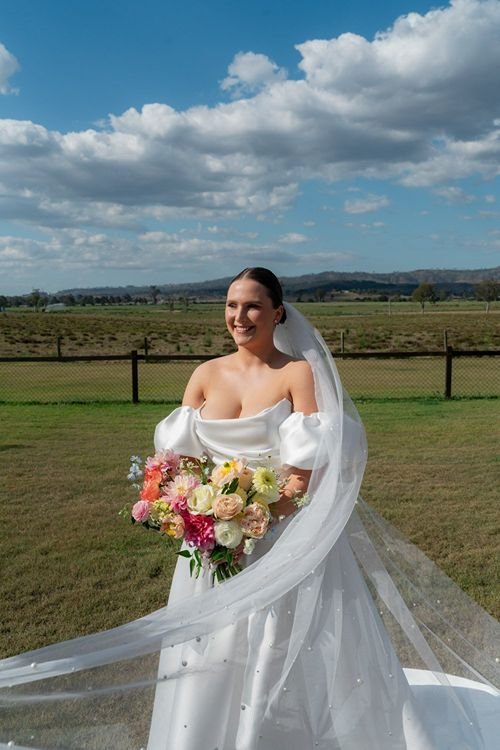 Beautiful bride wearing strapless wedding dress with long veil holding bouquet in Country Qld.