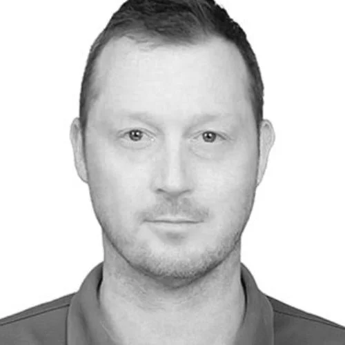 Black and white portrait of a man with short, dark hair, wearing a collared shirt, looking directly at the camera.