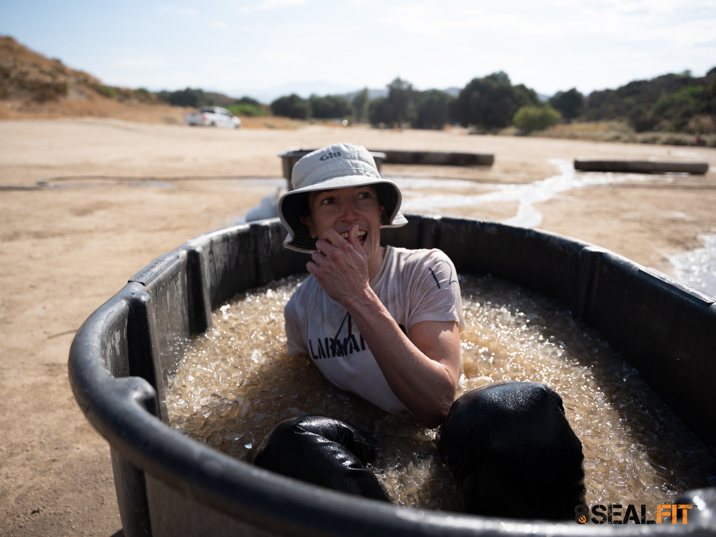 Pauline smiling about to immerse fully into a muddy icebath at her crucible