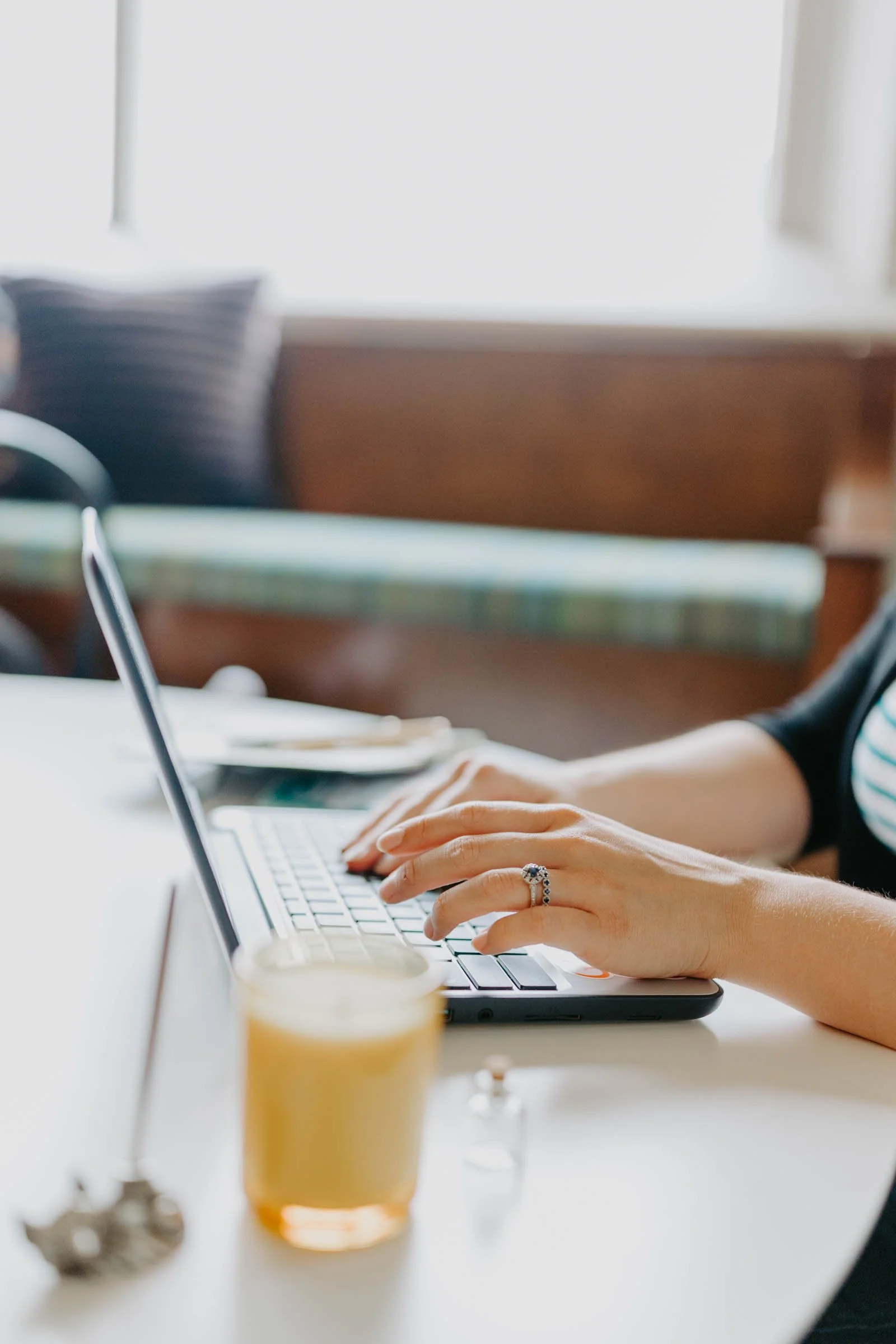 Person typing on a laptop with a candle and ink, and a calligraphy pen on the table.