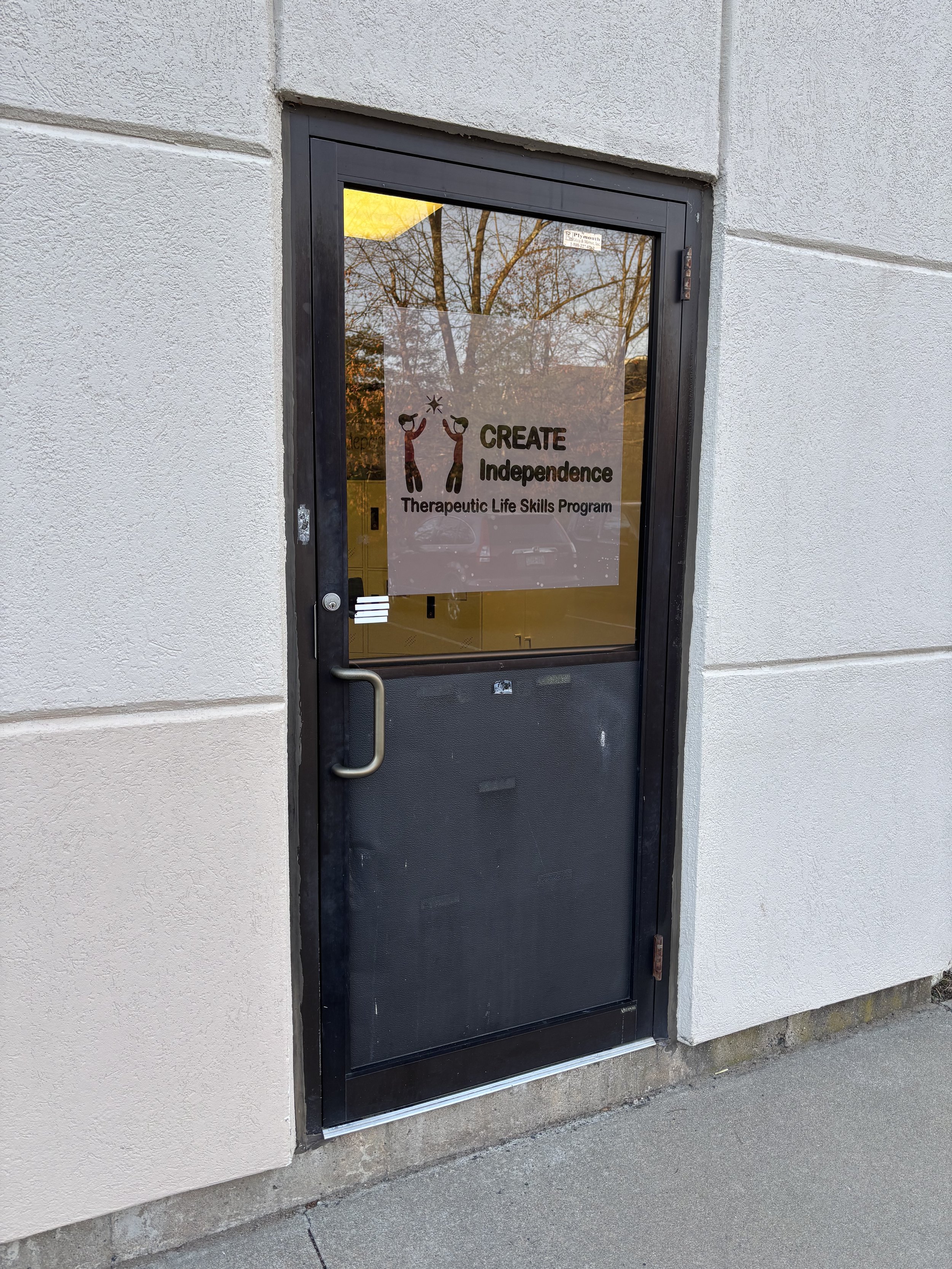 Door with a sign that reads 'CREATE Independence Therapeutic Life Skills Program' and depicts two colorful figures holding hands and reaching upwards.