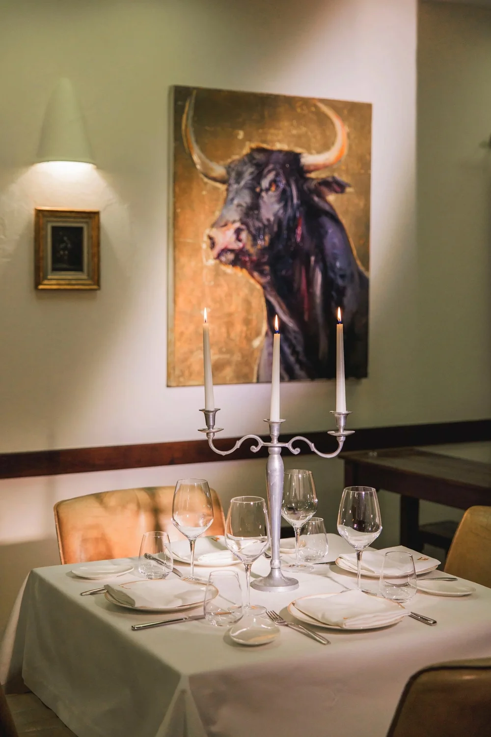 Dining room at Azahar Spanish restaurant in Sofia, set for dinner beneath a painting of a bull