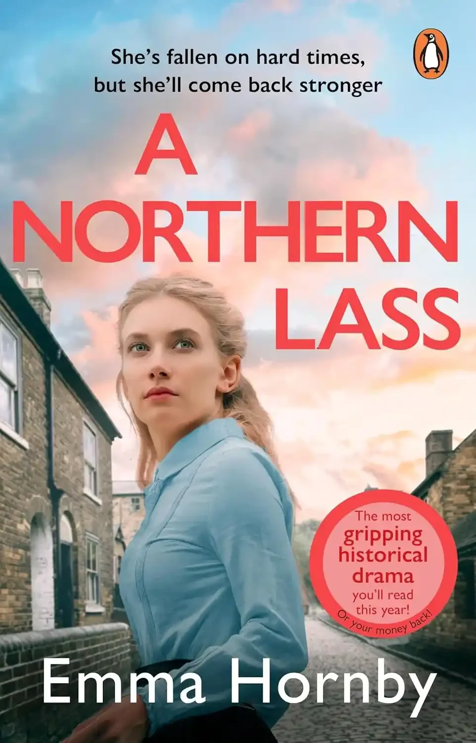 Book cover for "A Northern Lass" by Emma Hornby, featuring a woman with blonde hair in a blue shirt standing on a street with houses, with a colorful sunset sky in the background and an orange circle with red text about the book's content.