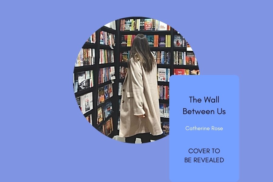A woman in a beige coat browsing books in a bookstore with bookshelves filled with books. A blue overlay contains the text "The Wall Between Us" by Catherine Rose and the phrases "Cover to be Revealed".
