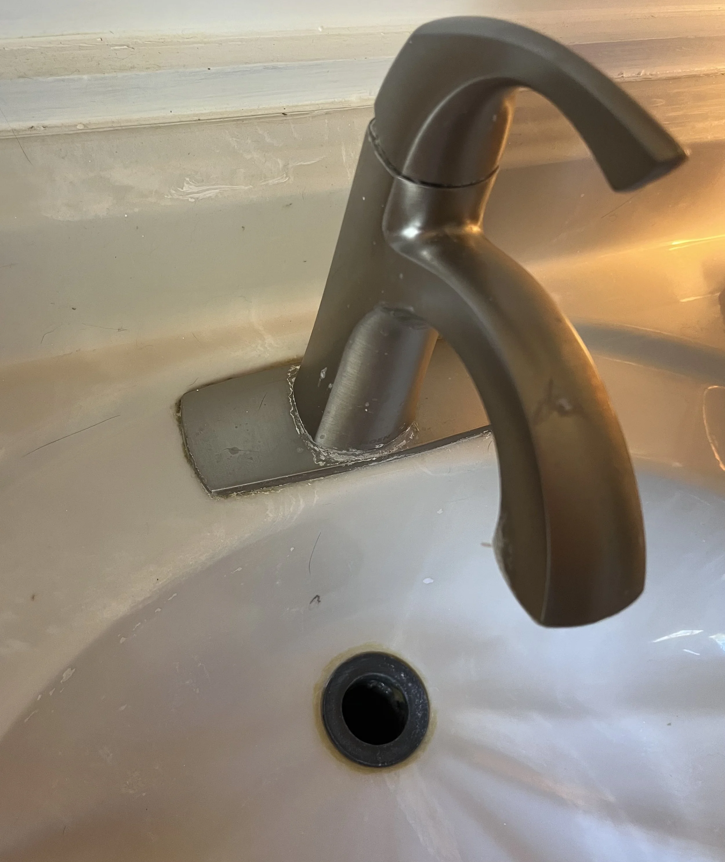 Close-up of a stainless steel kitchen faucet over a white sink.