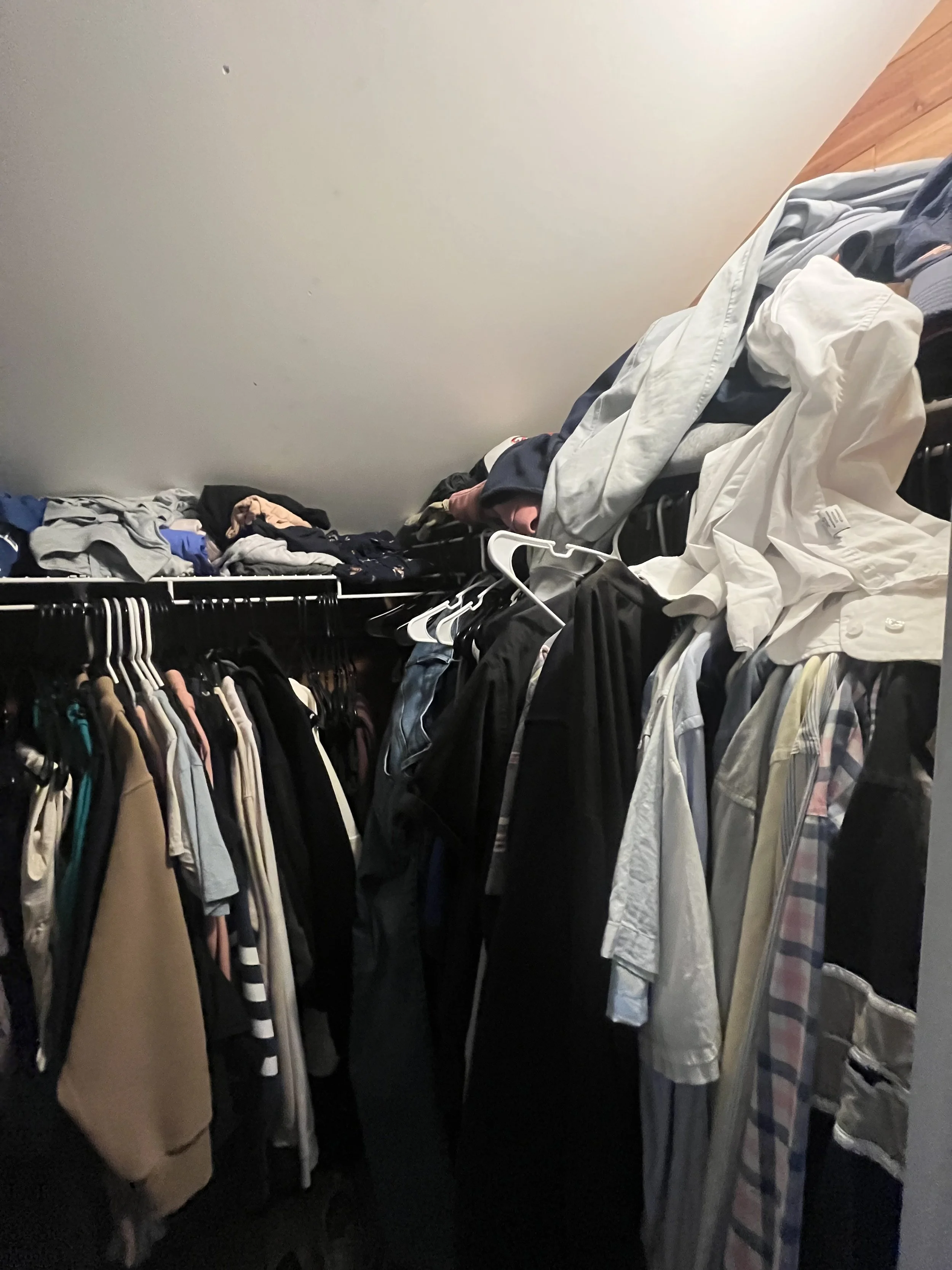 Clothes organized on hangers and shelf in a closet.