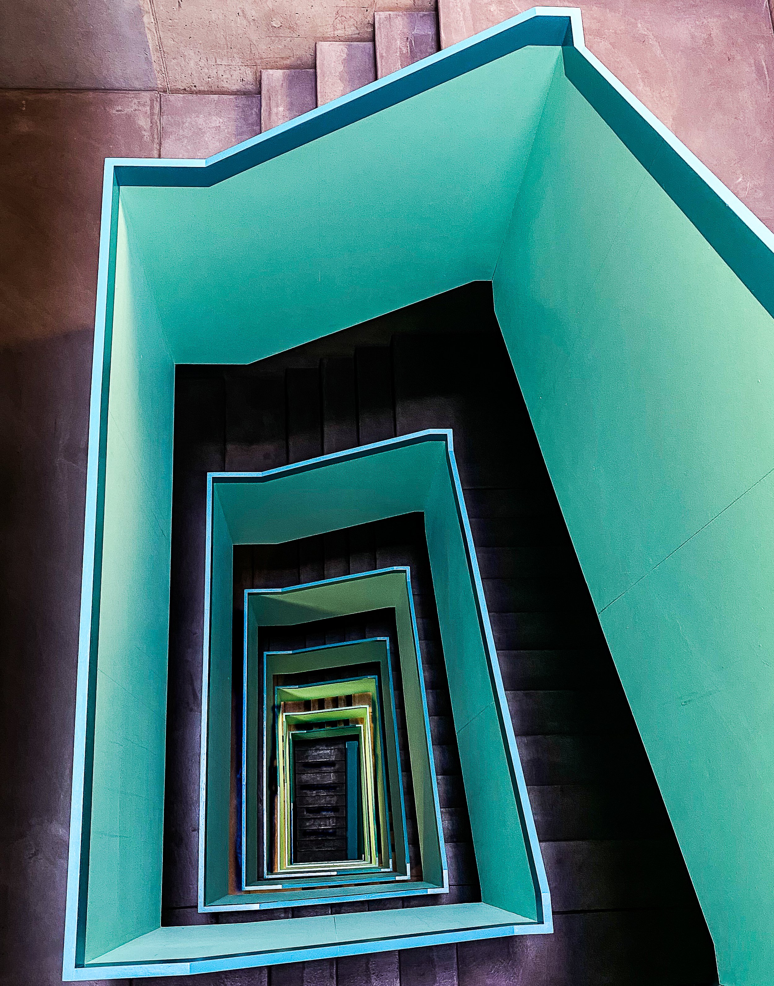 A top-down view of a staircase with multiple levels, featuring blue and yellow rails, creating a spiral pattern.