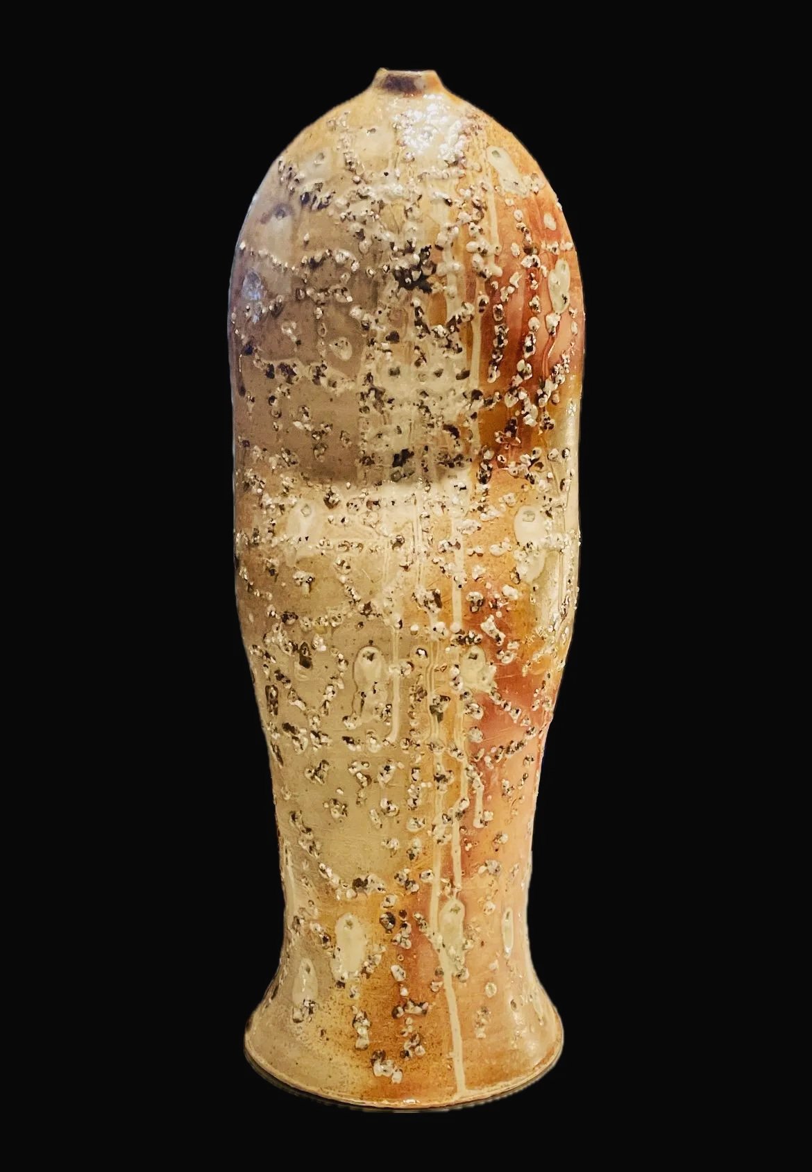 A ceramic art piece by zuzka Vaclavik resembling a human penis with a textured surface and a gradient of beige, brown, and peach colors on a black background.