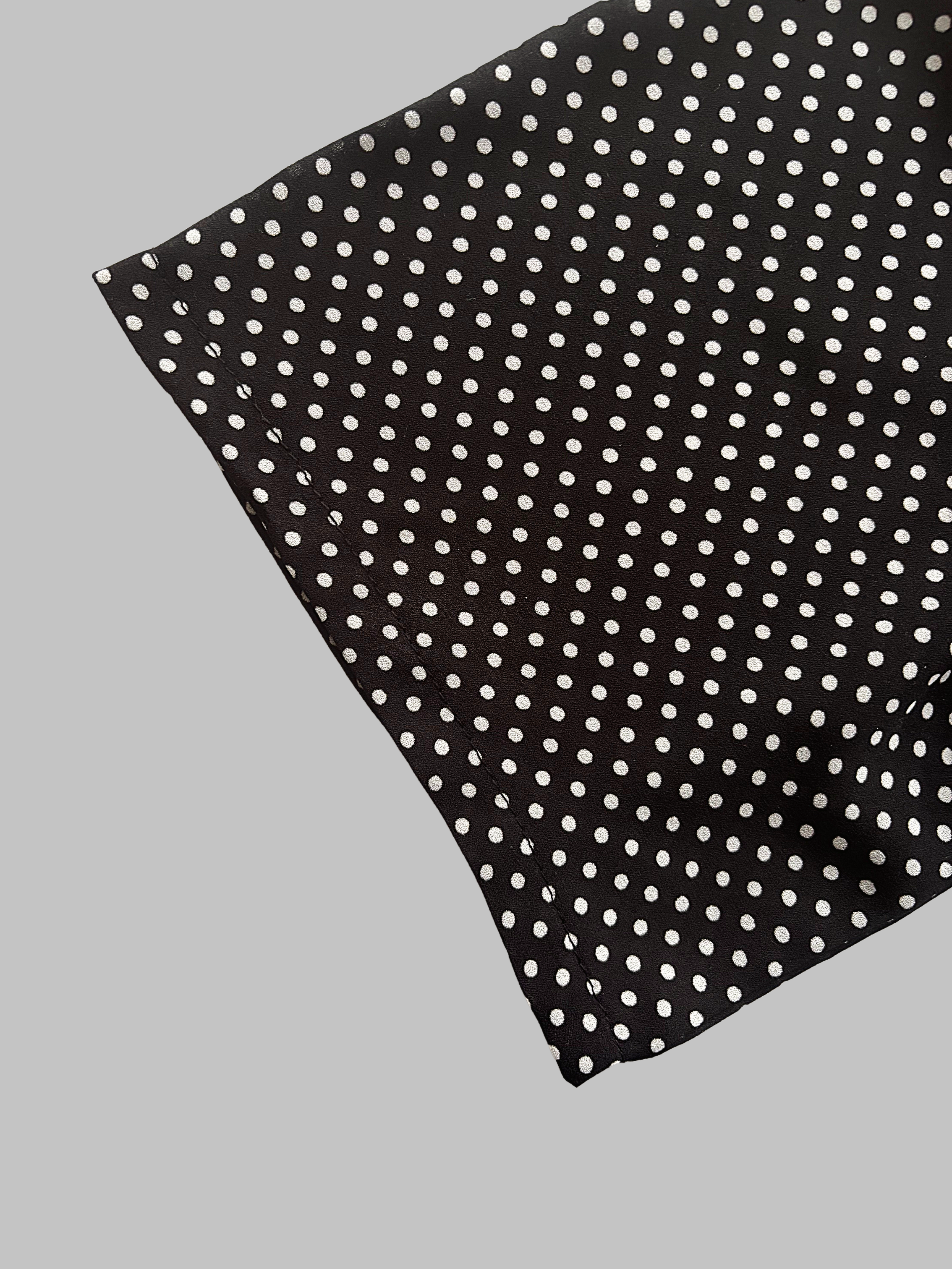 Close-up of a black blouse sleeve with white polka dots.
