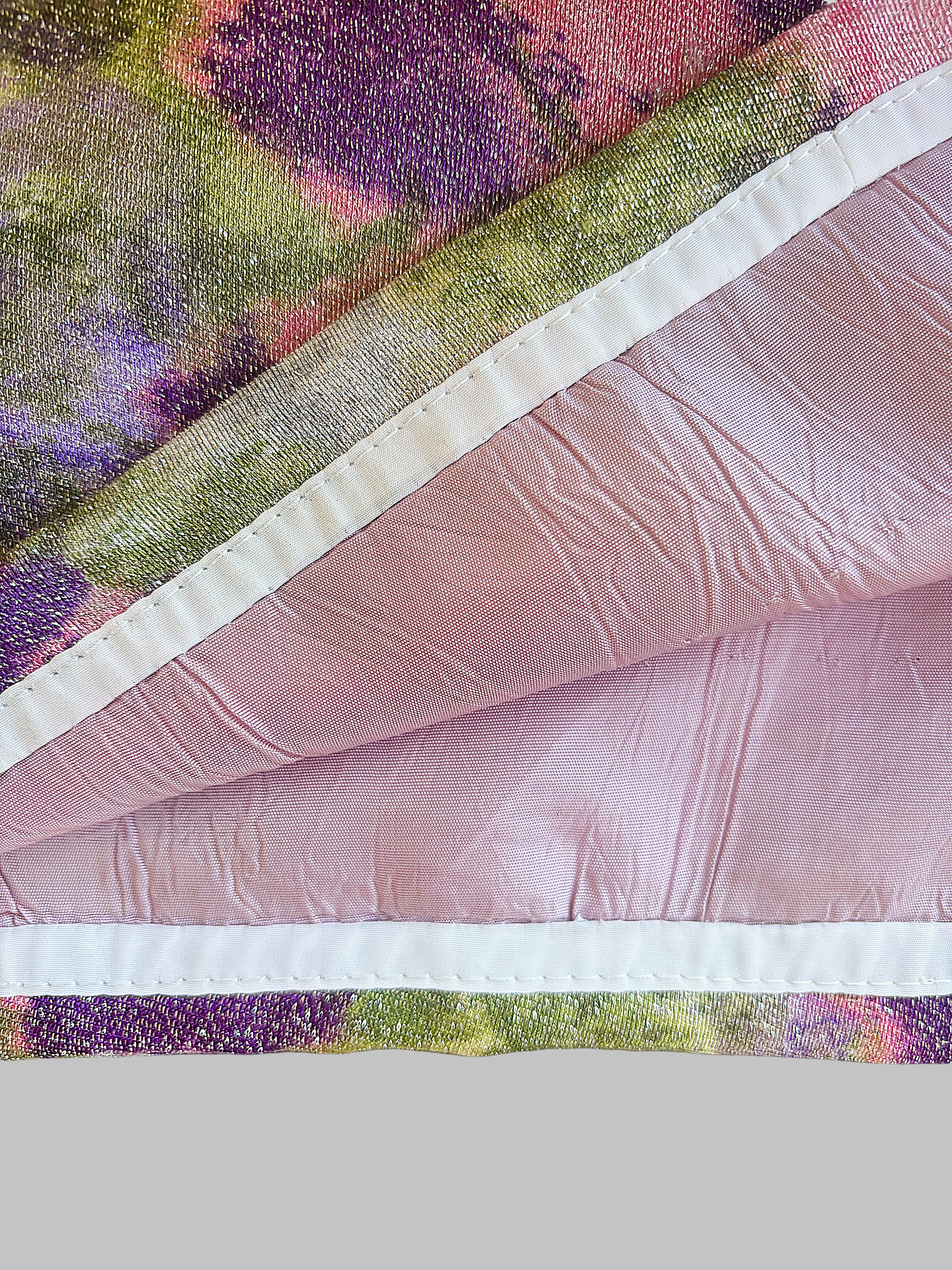 Close-up of a fabric with floral print and pink lining, showing the textured surface and stitching.