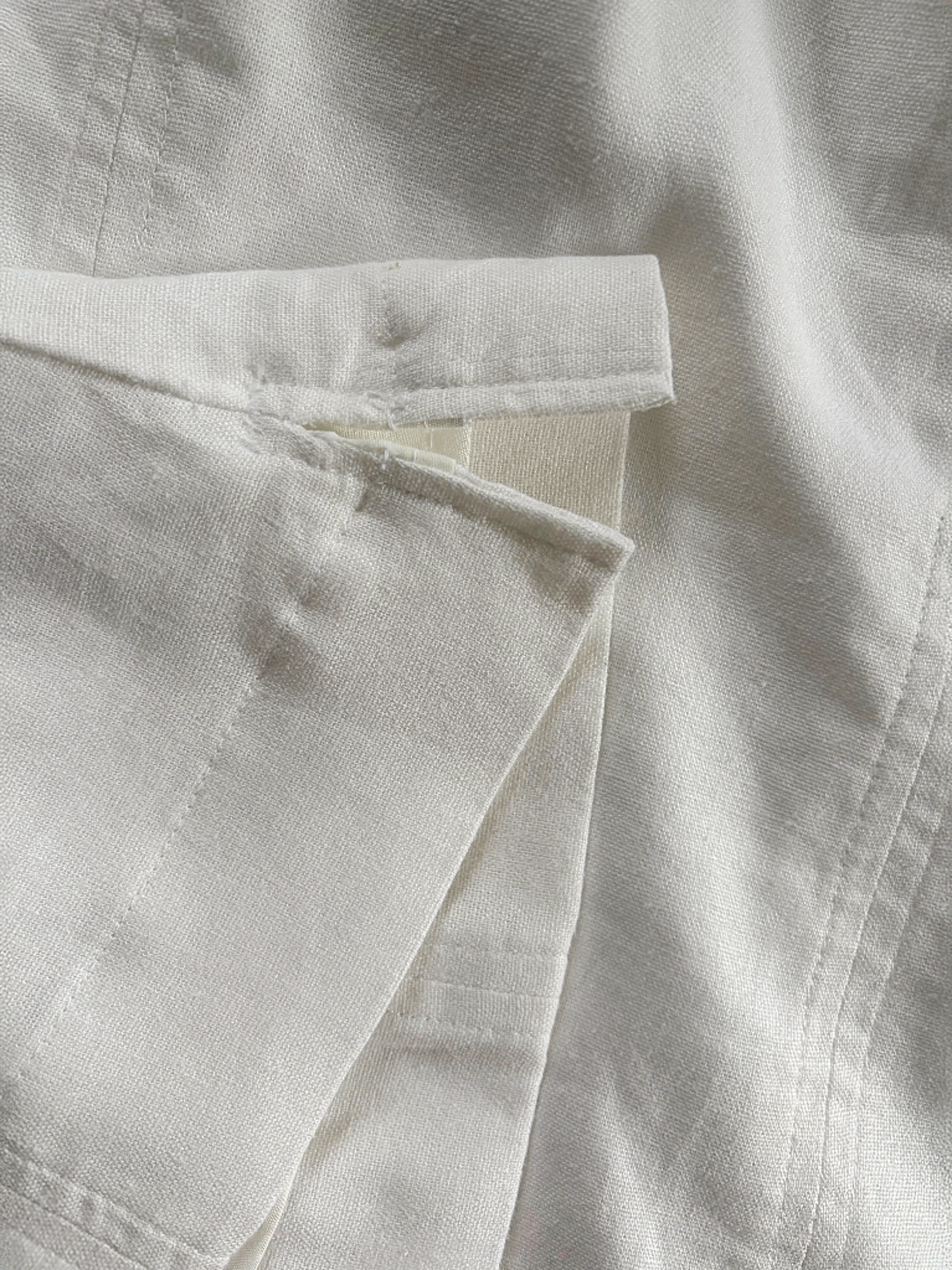 Close-up of a white linen top hem and slit details.