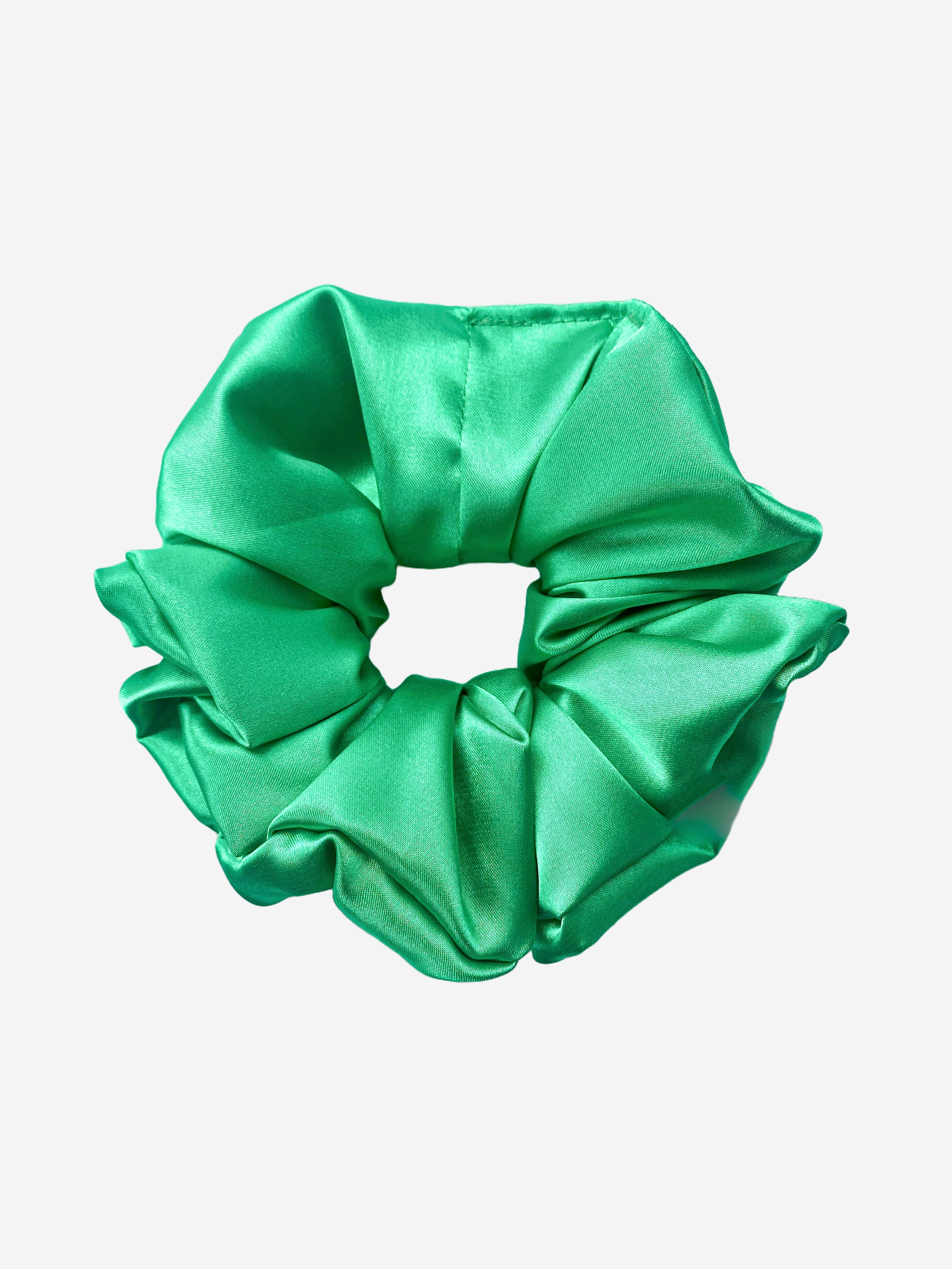 A emerald green satin scrunchie with a lustre and smooth texture.