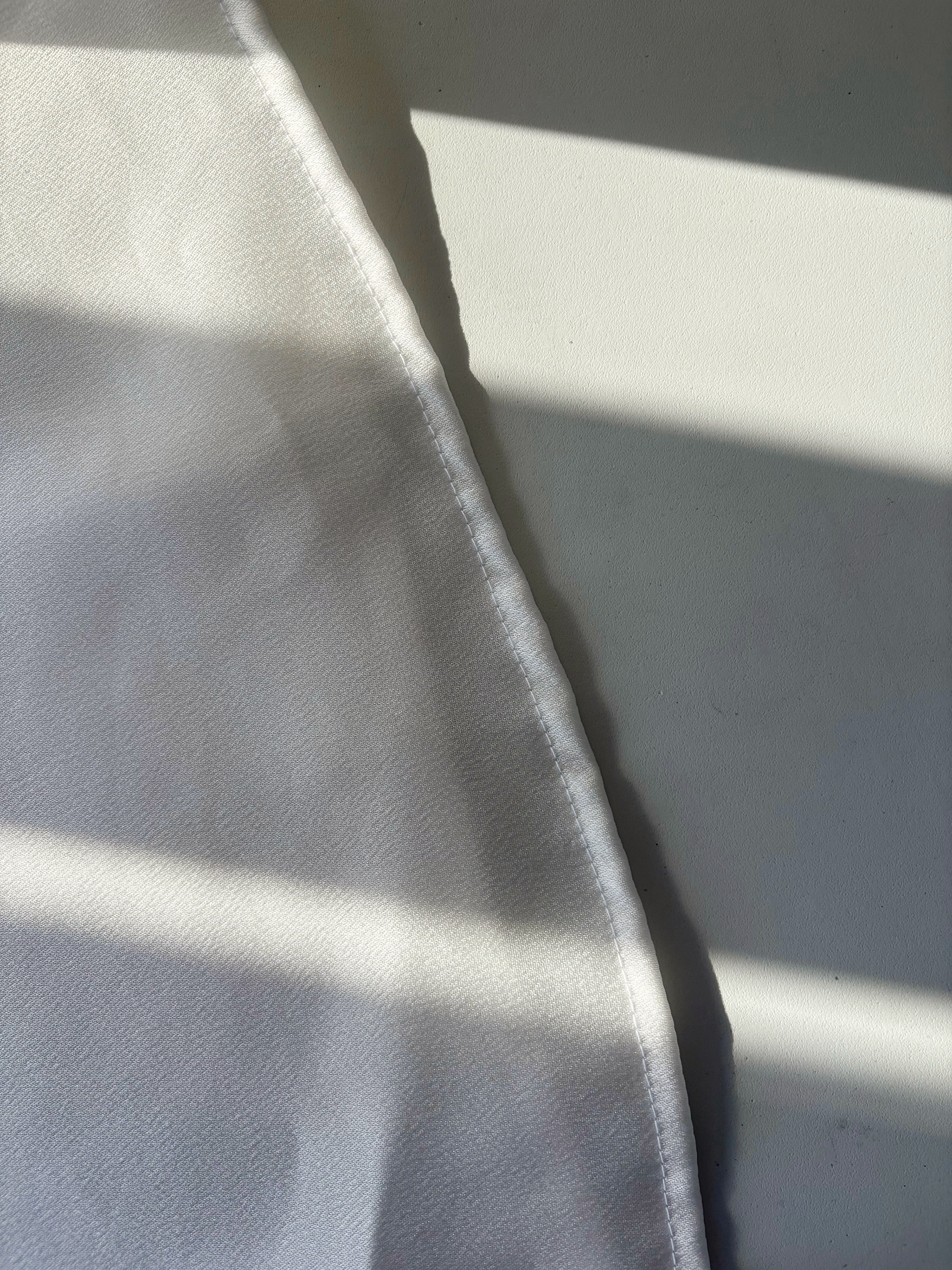 Close-up of stitched hem on dress and thrown sunlight on fabric.