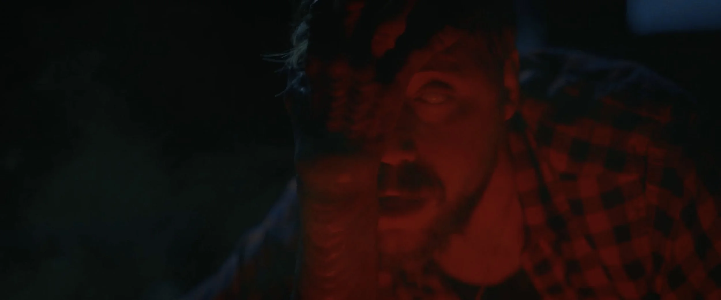 Evan Towell’s face is seized by a demon in The Fetus, lit in harsh red light that amplifies fear and disorientation during a pivotal horror moment.