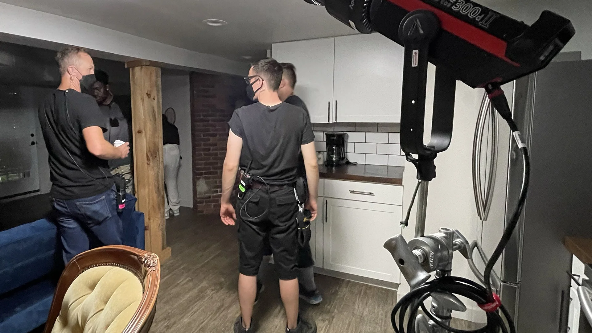 Behind-the-scenes photo of the film crew inside Chris’s apartment set from The Fetus, with lighting equipment and crew members preparing for a shot in a compact kitchen-living space.