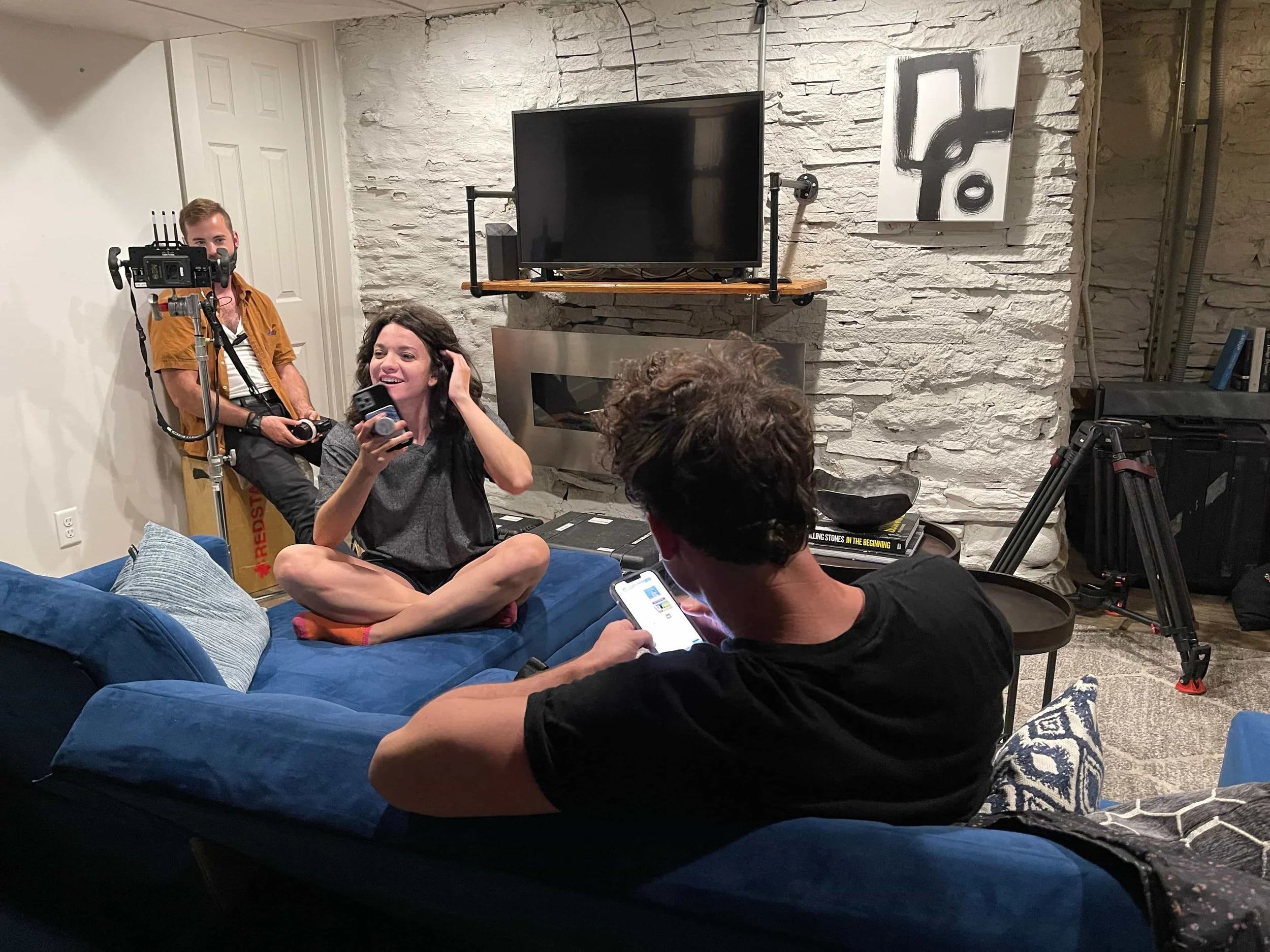 Lauren LaVera and Julian Curtis relaxing between takes on the apartment set of The Fetus, with a crew member visible in the background
