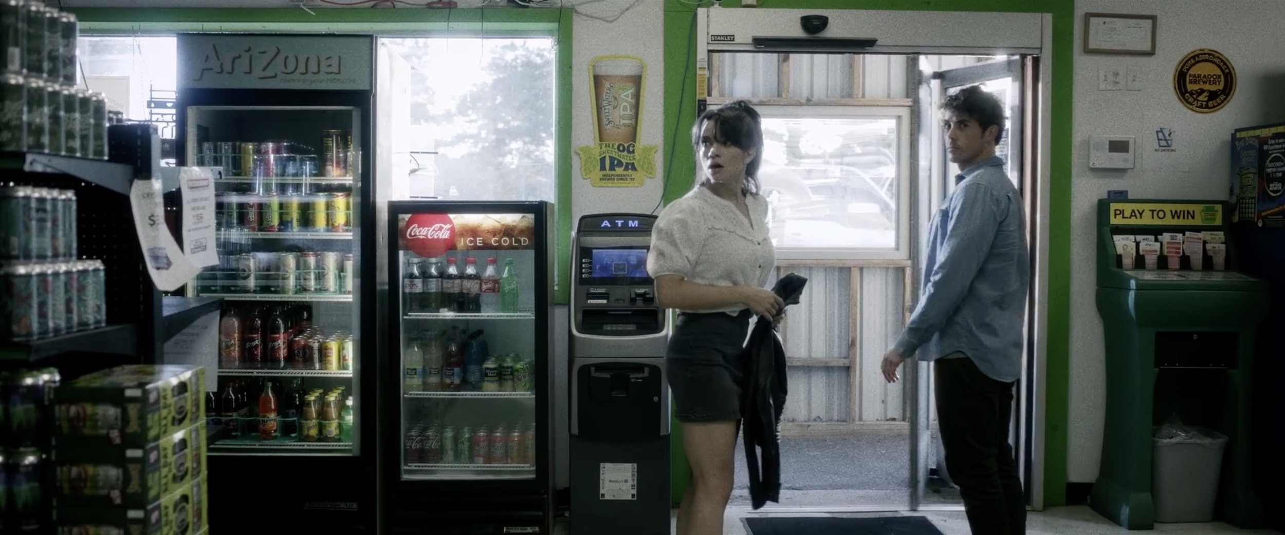 Lauren LaVera and Julian Curtis react in a convenience store scene from The Fetus, illustrating the delicate balance between tension and comedy in horror-comedy filmmaking.