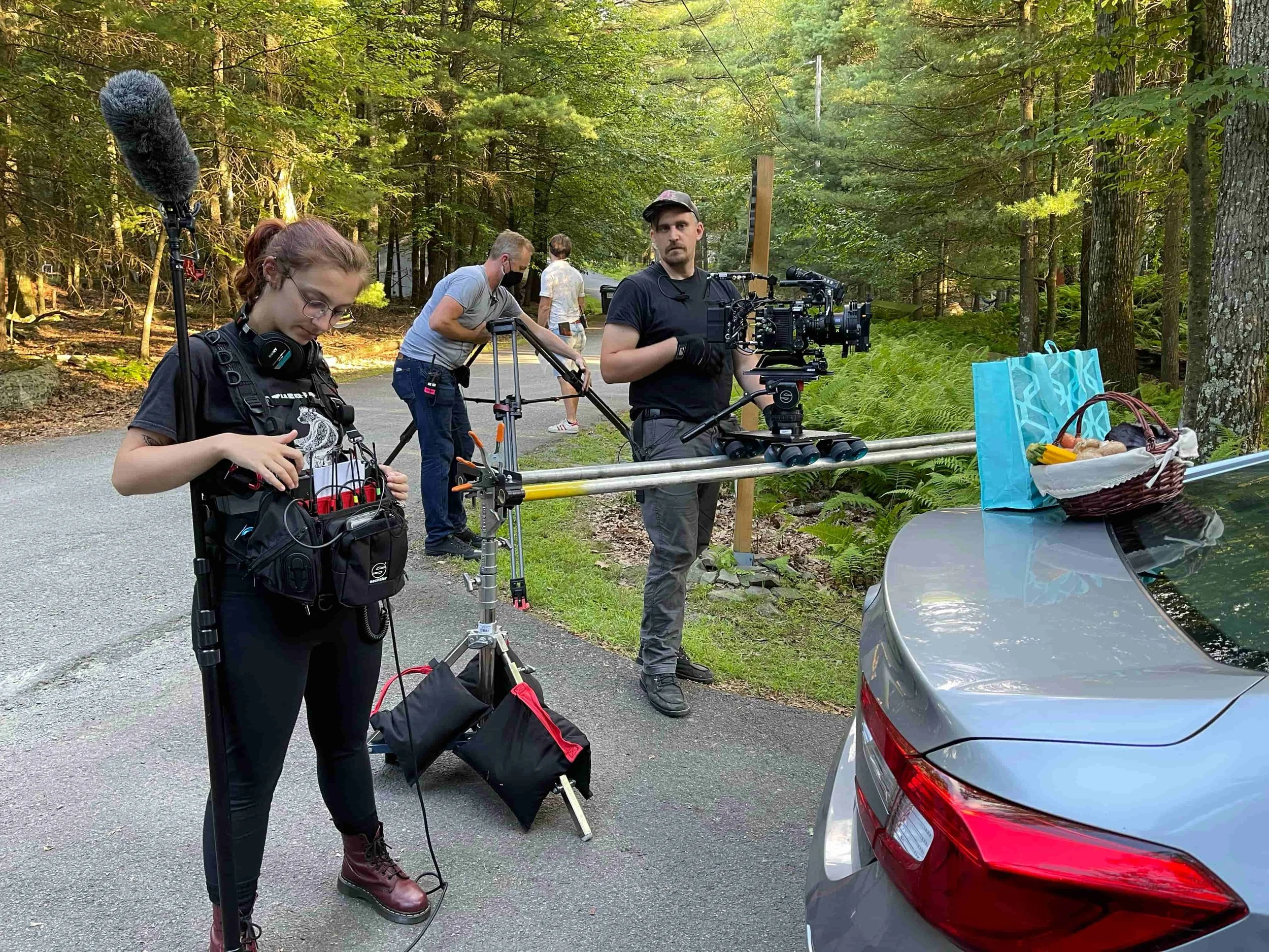 Sound mixer Genna Edwards checks her audio equipment while the camera crew sets up a dolly shot on a wooded road on location during the filming of The Fetus