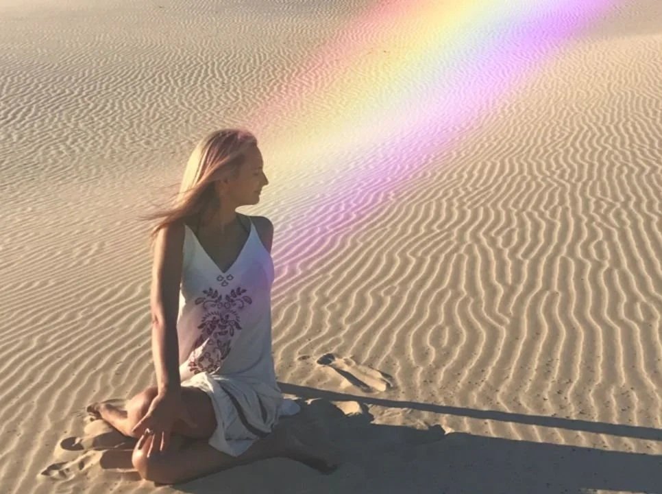 Girl on beach emitting rainbow.