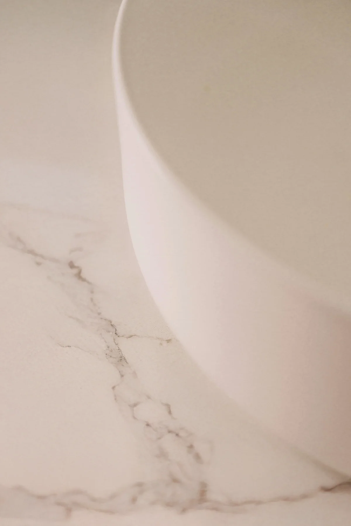 Close-up of a white ceramic or porcelain bowl placed on a marble surface with visible veins.