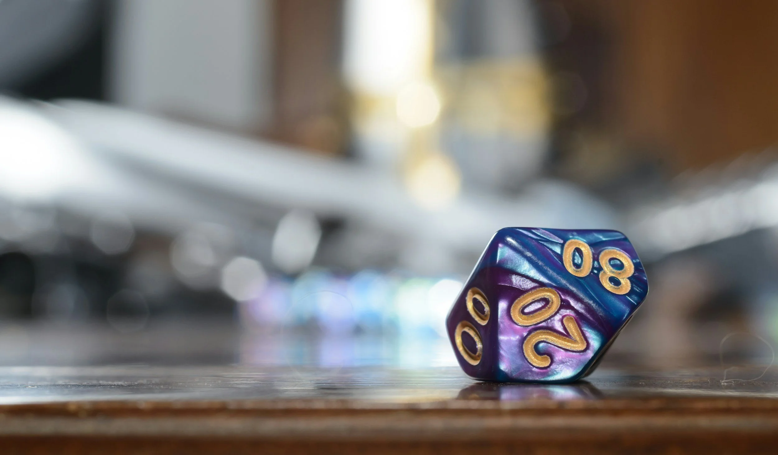 A purple and blue six-sided die with gold numbers, showing the numbers 20 and 8, is rolling on a wooden surface with other blurred gaming dice in the background.