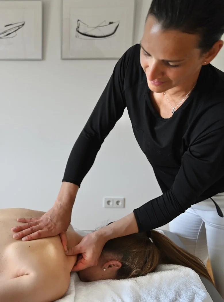 Masseurin führt eine Massage an einem nackten Rücken eines liegenden Patienten durch.