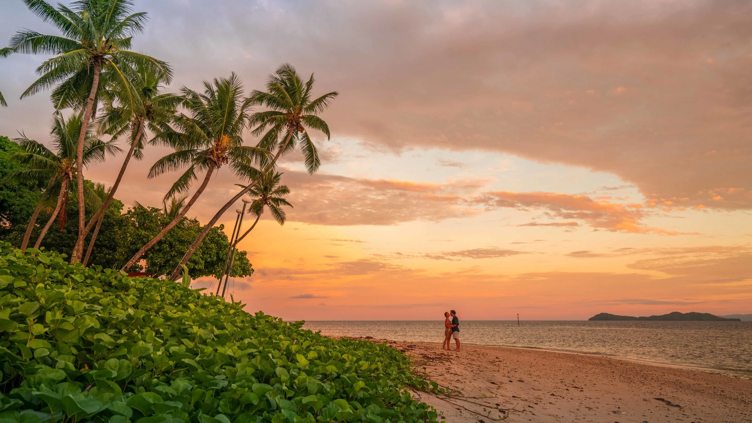 A beautiful sunset with a couple and palm trees in Fiji 