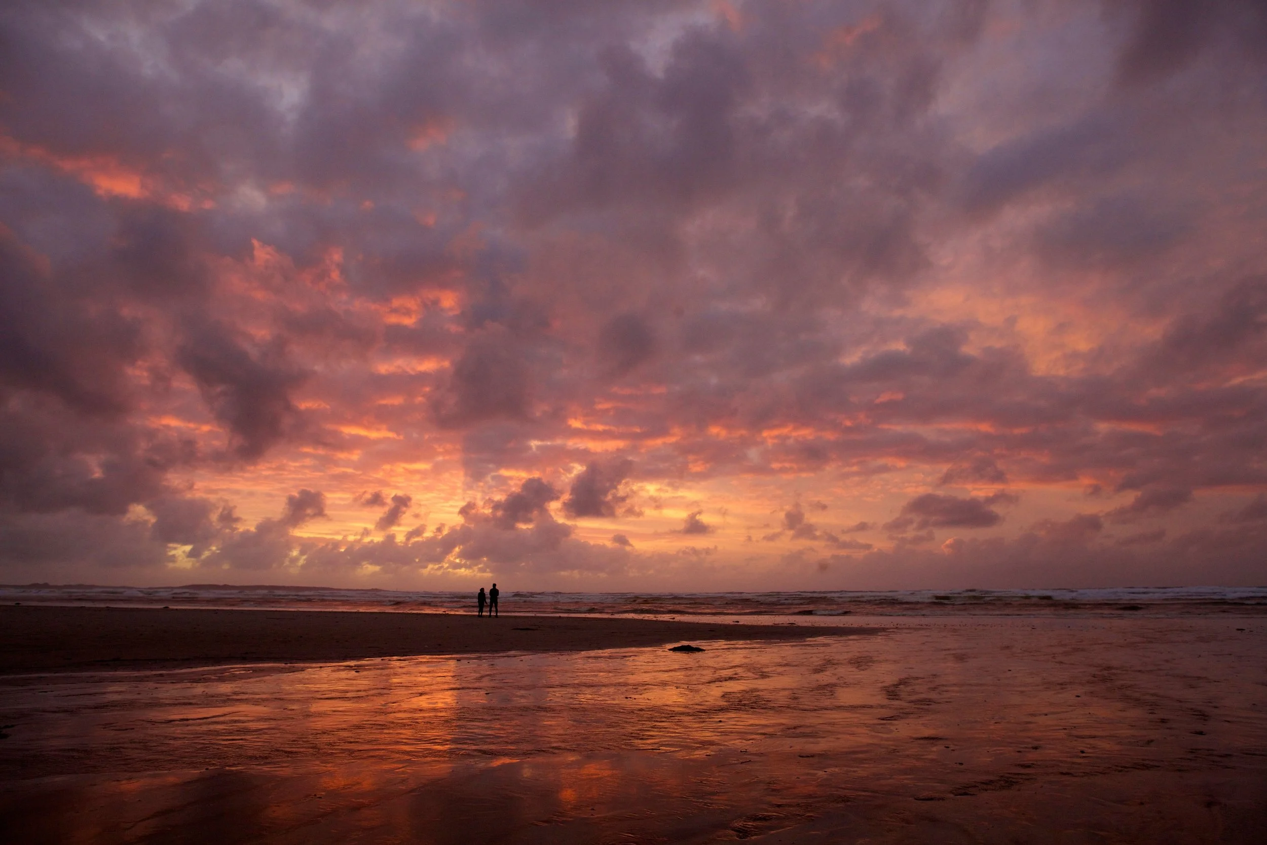 Couple in front of red orange and pink sunset in Tasmania