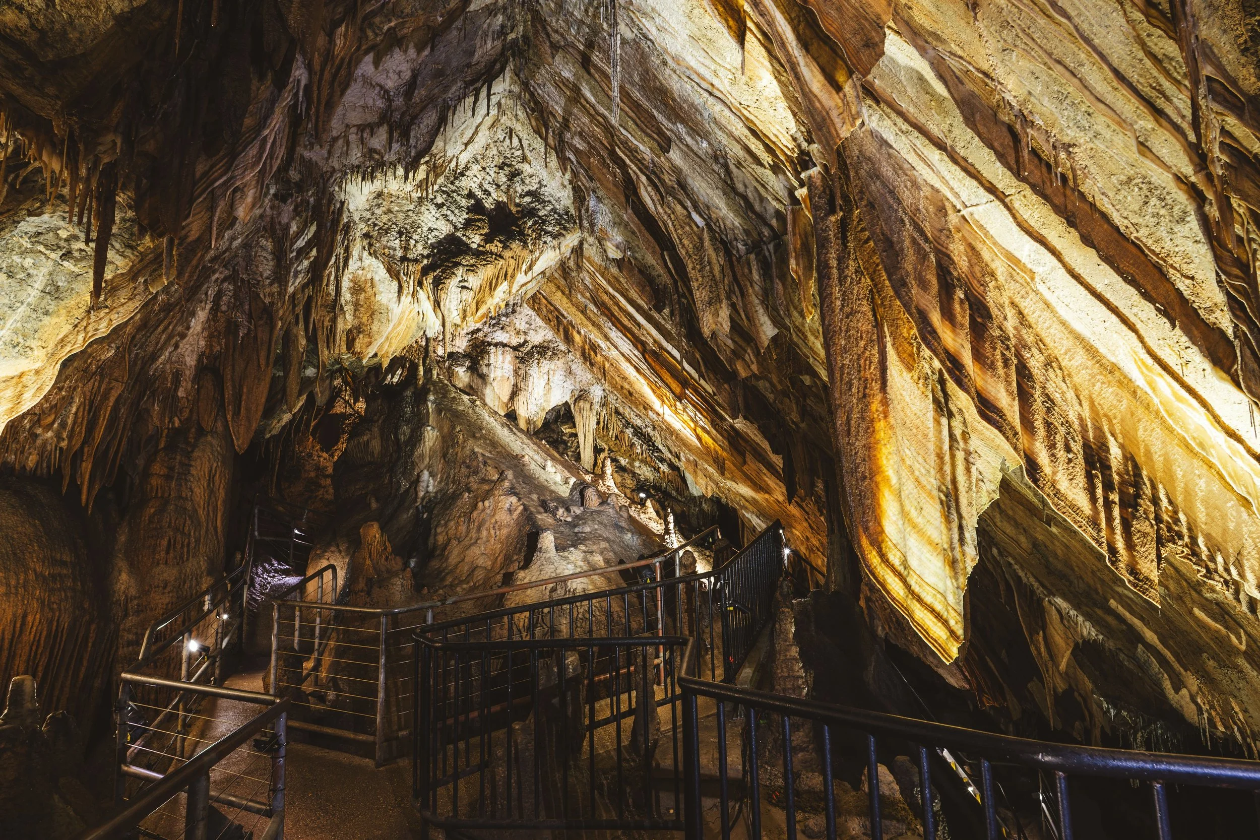 Illuminated limestone cave with winding walkways and dramatic rock formations