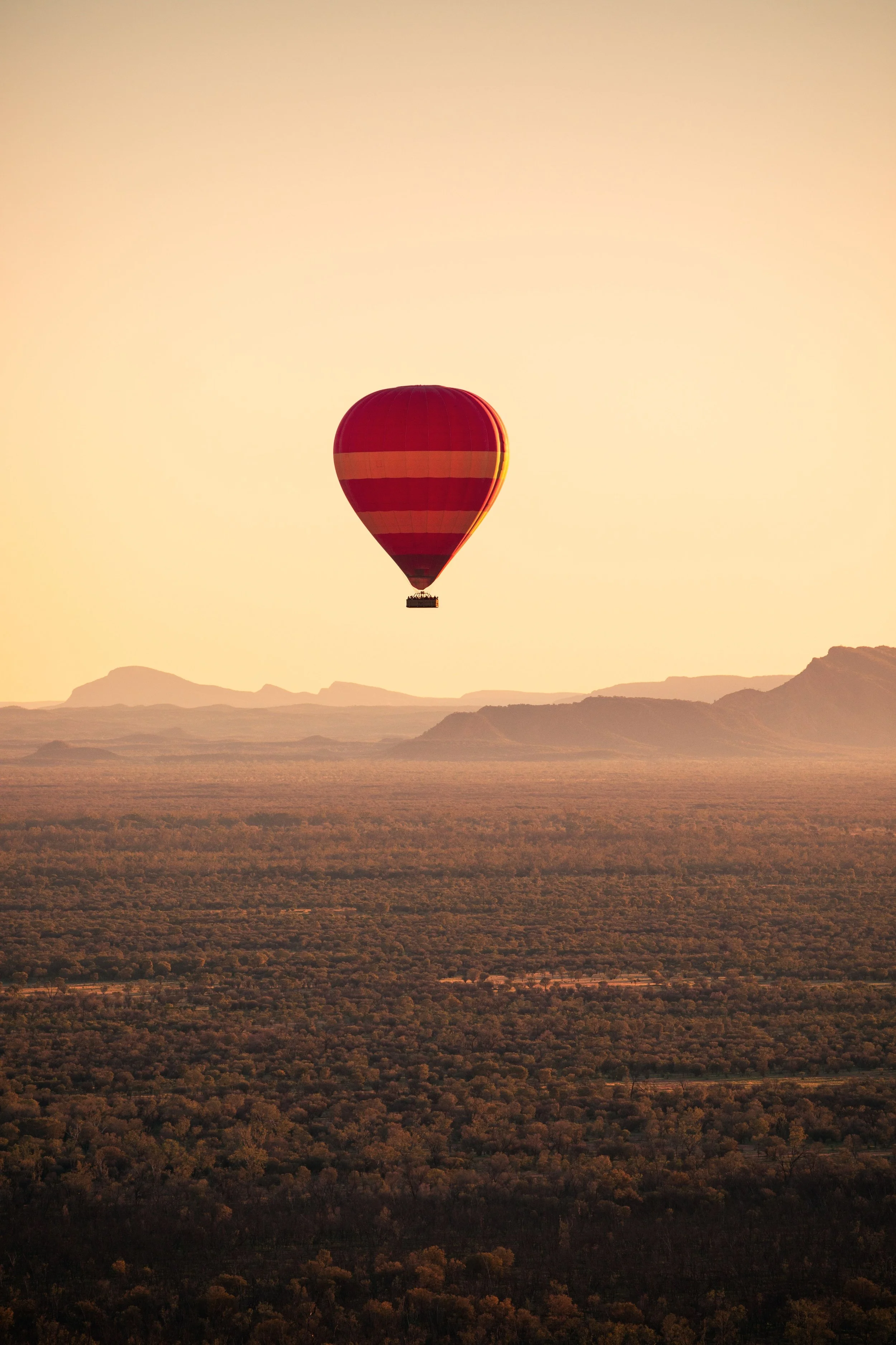 Hot air balloon floating over vast outback landscape at sunrise