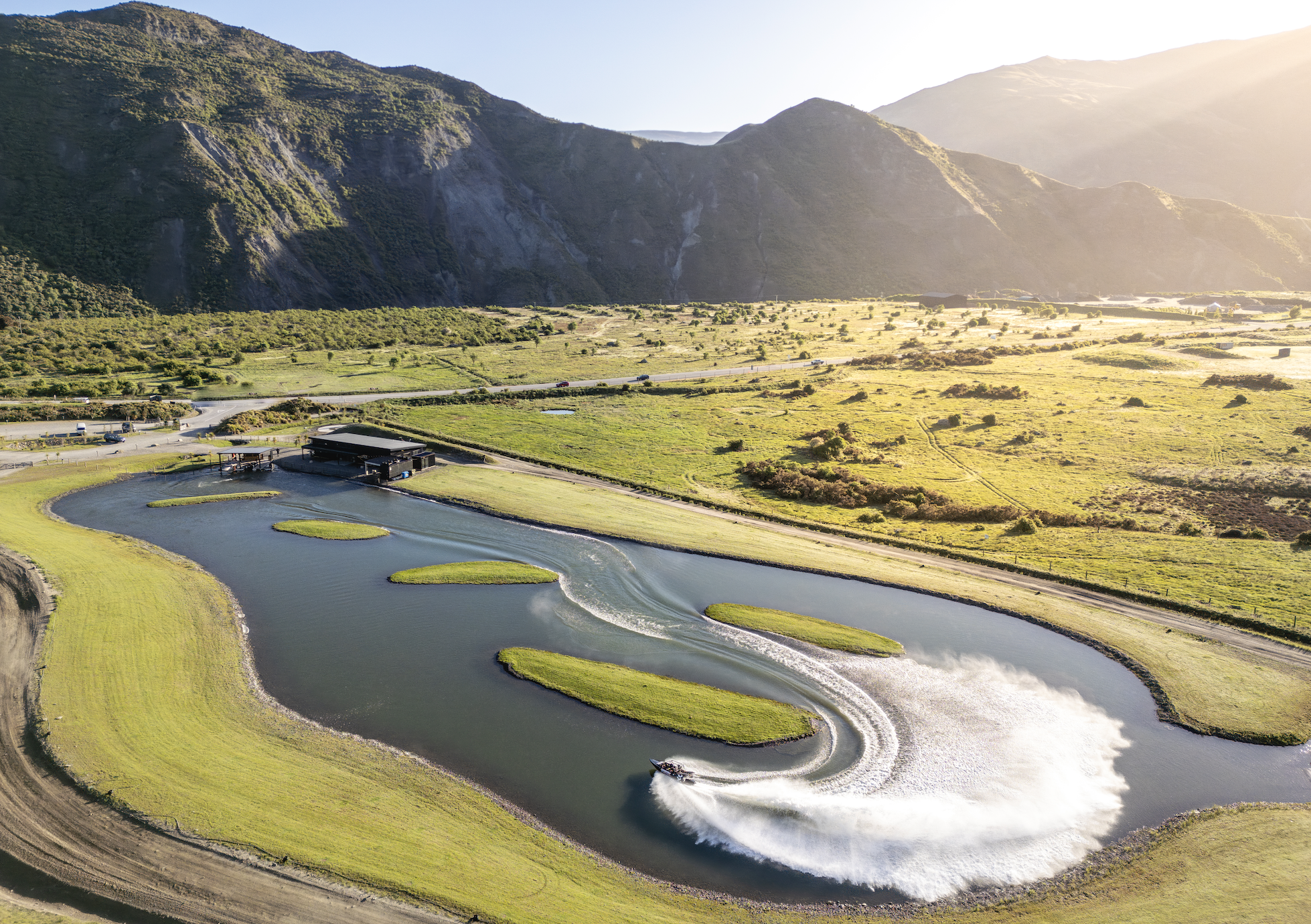 Wakeboarding on curved lagoon track set against open grassland and mountains