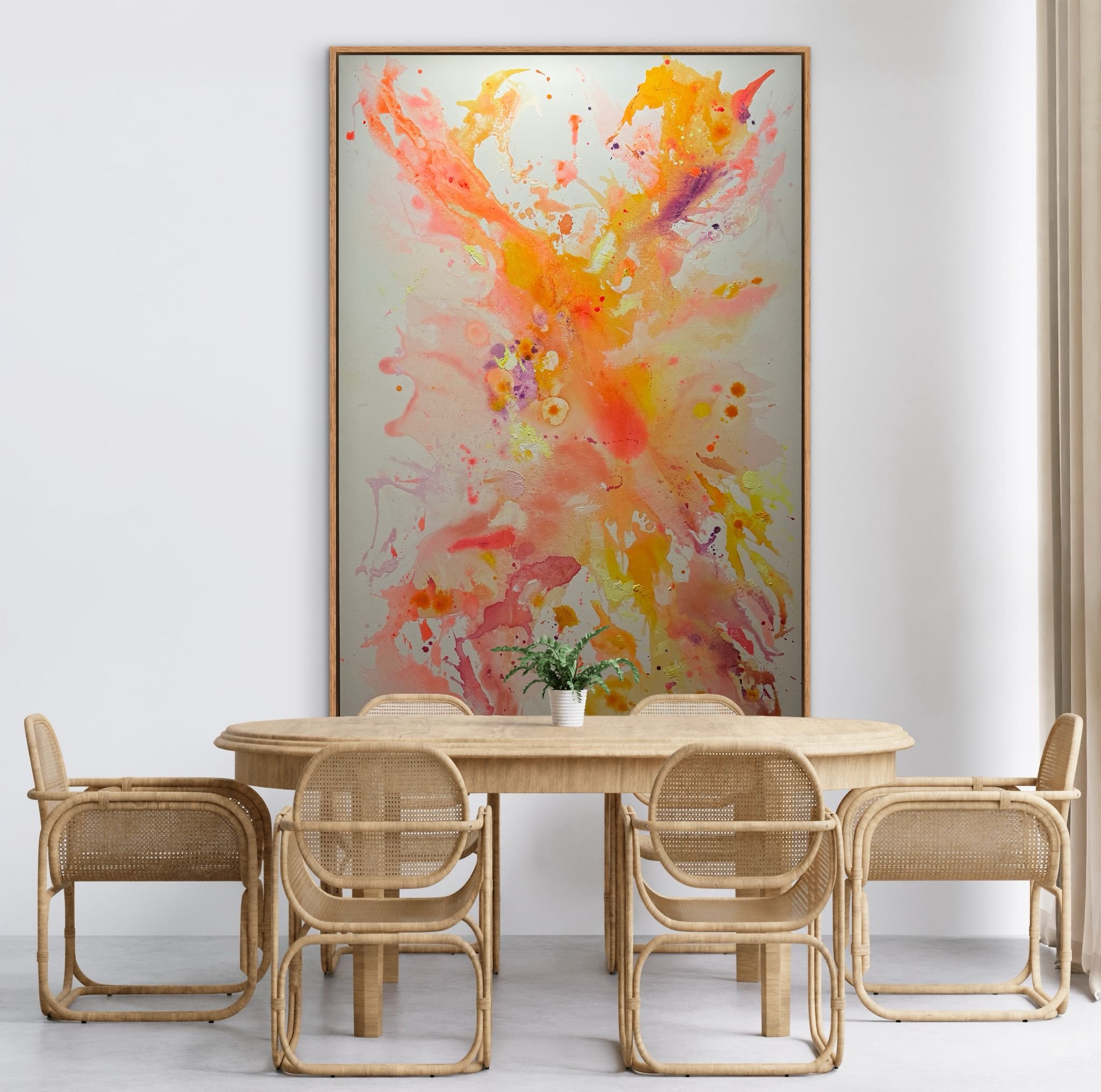 Ein Esszimmer mit sechs geflochtenen Stühlen um einen Holztisch, eine grüne Pflanze in einer weißen Vase in der Mitte, und eine große abstrakte Gemäldefront mit bunten Farben an der weißen Wand