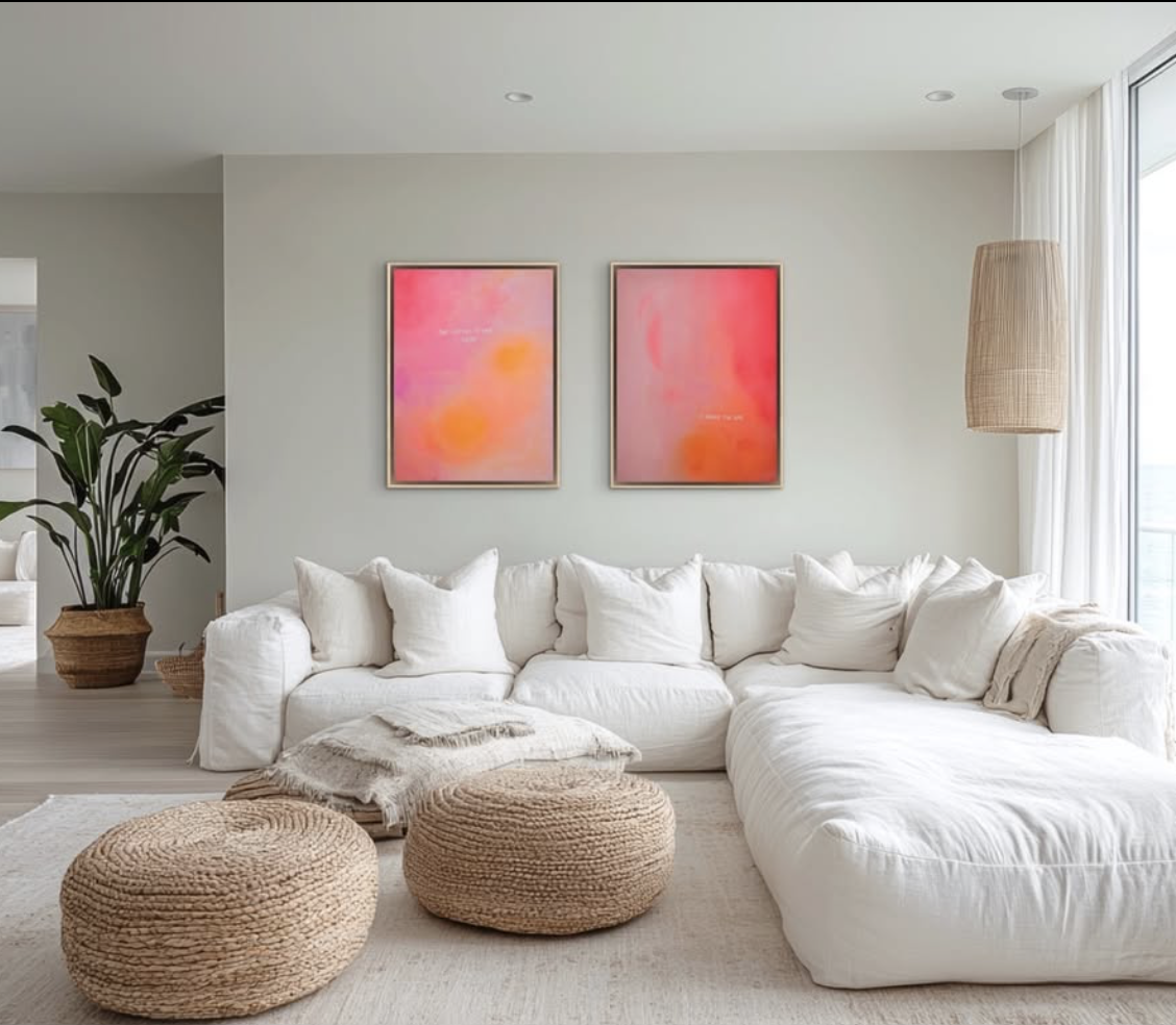 Helles Wohnzimmer mit weißem Sofa, zwei gestreiften Poufs, einem großen Pflanzenkübel mit Grünpflanze und zwei pinkfarbigen abstrakten Bilder an der Wand.