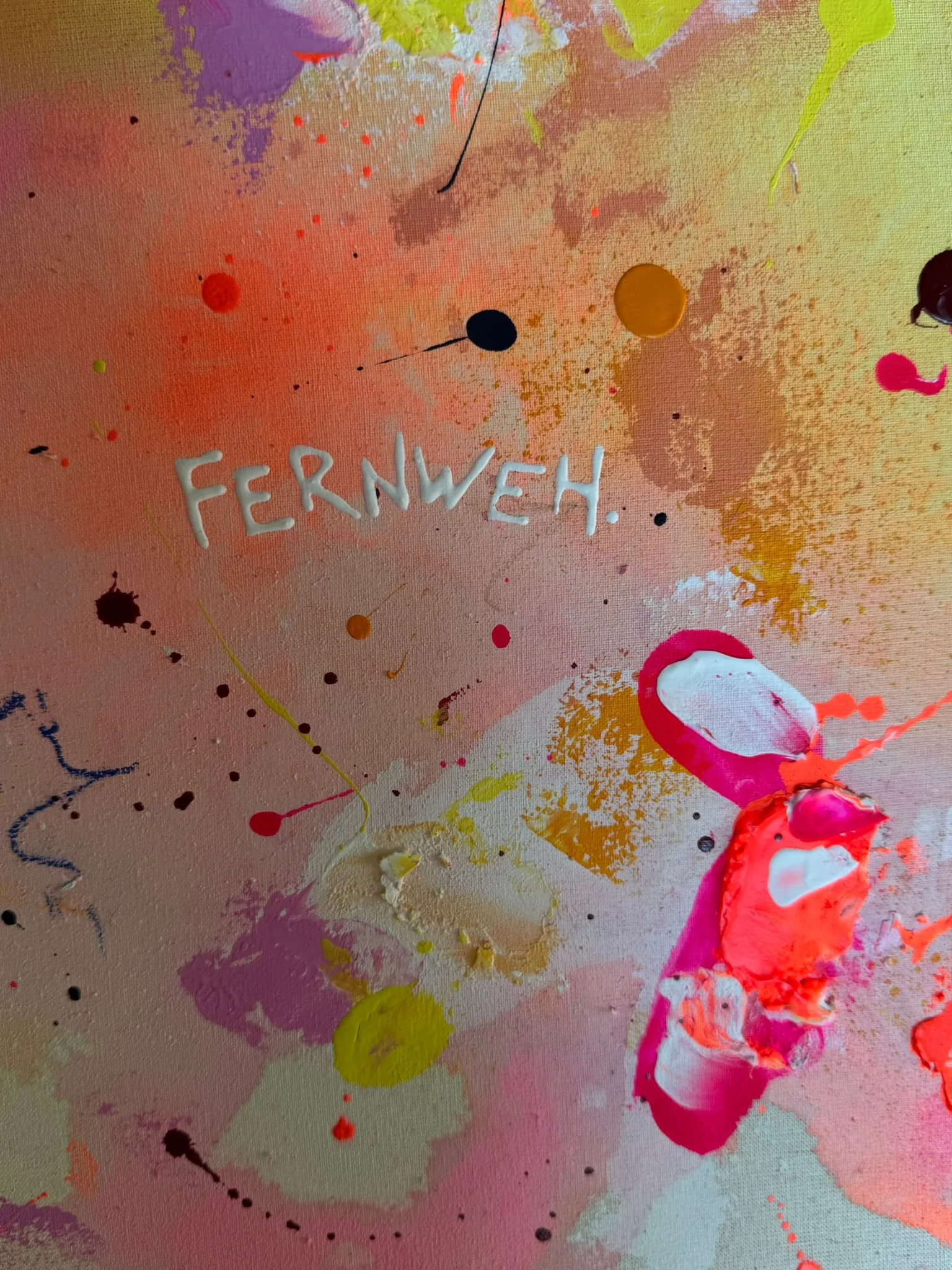 Abstrakte bunte Farbkleckse und -spritzer auf Leinwand, in der Mitte steht das Wort 'FERNWEH' in Weiß.