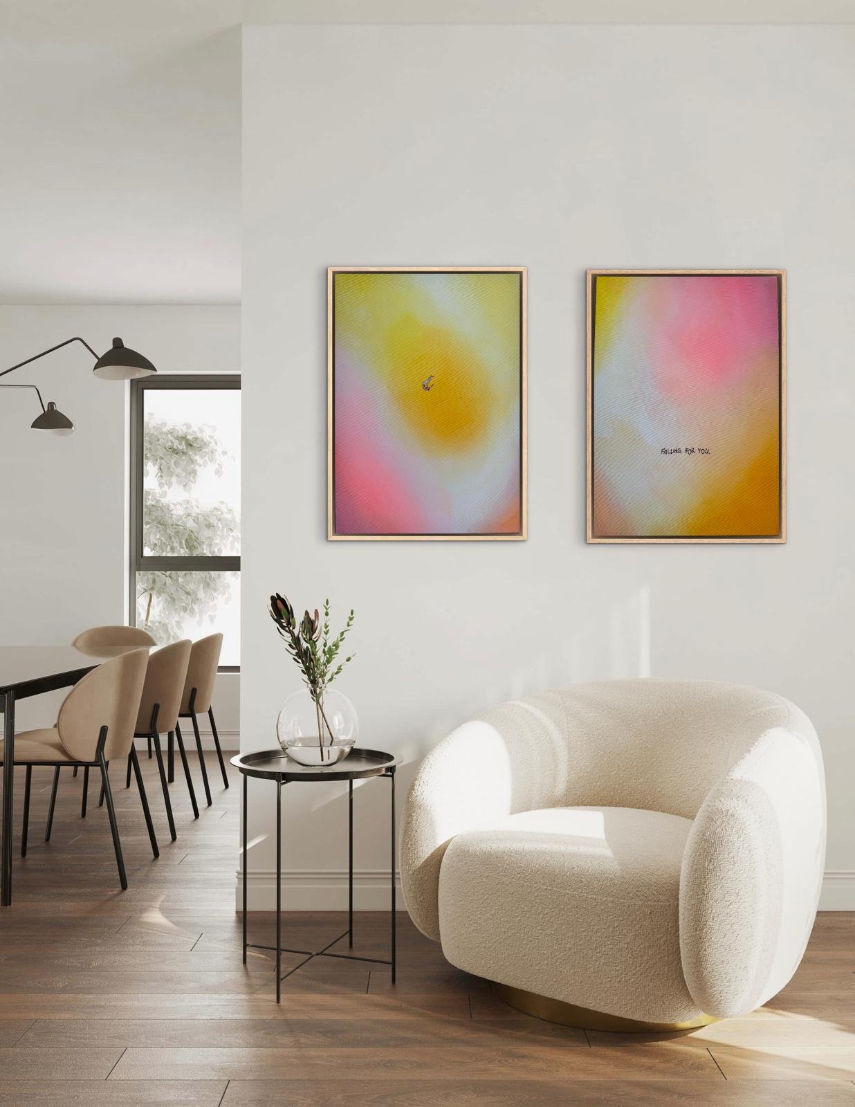 Moderner Wohnraum mit einer weißen Sessel, einem kleinen schwarzen Beistelltisch mit einer Vase und zwei Wandbilder mit abstrakter, pastellfarbener Kunst.