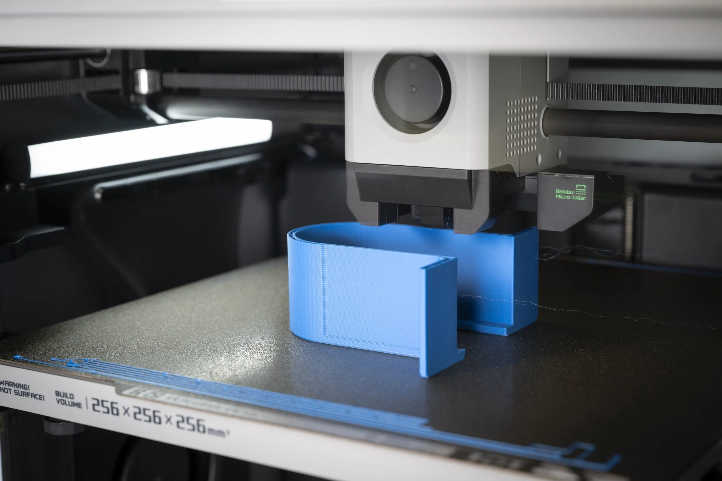 A 3D printer creating a blue object on a build plate.