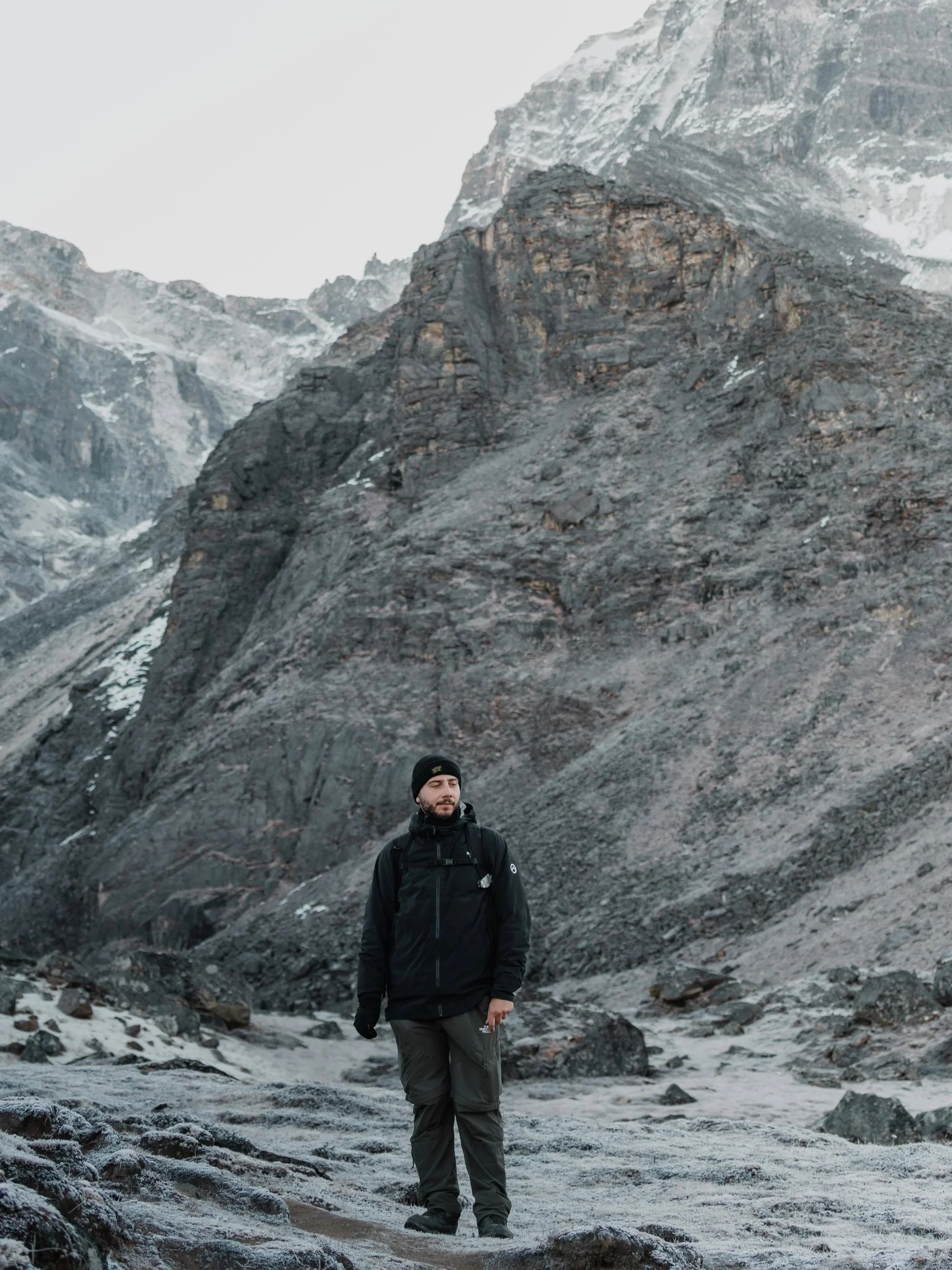 Un homme habillé en vêtements de randonnée dans un paysage de montagne rocheuse avec de la neige.
