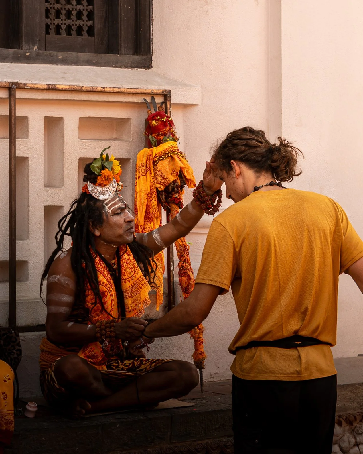 Un homme indou en train de faire un rituel ou une prière avec un autre homme dans un lieu religieux ou spirituel.