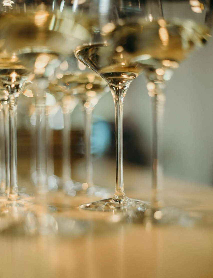 Close-up of multiple empty champagne glasses on a table, with a focus on one centered glass reflecting warm light.