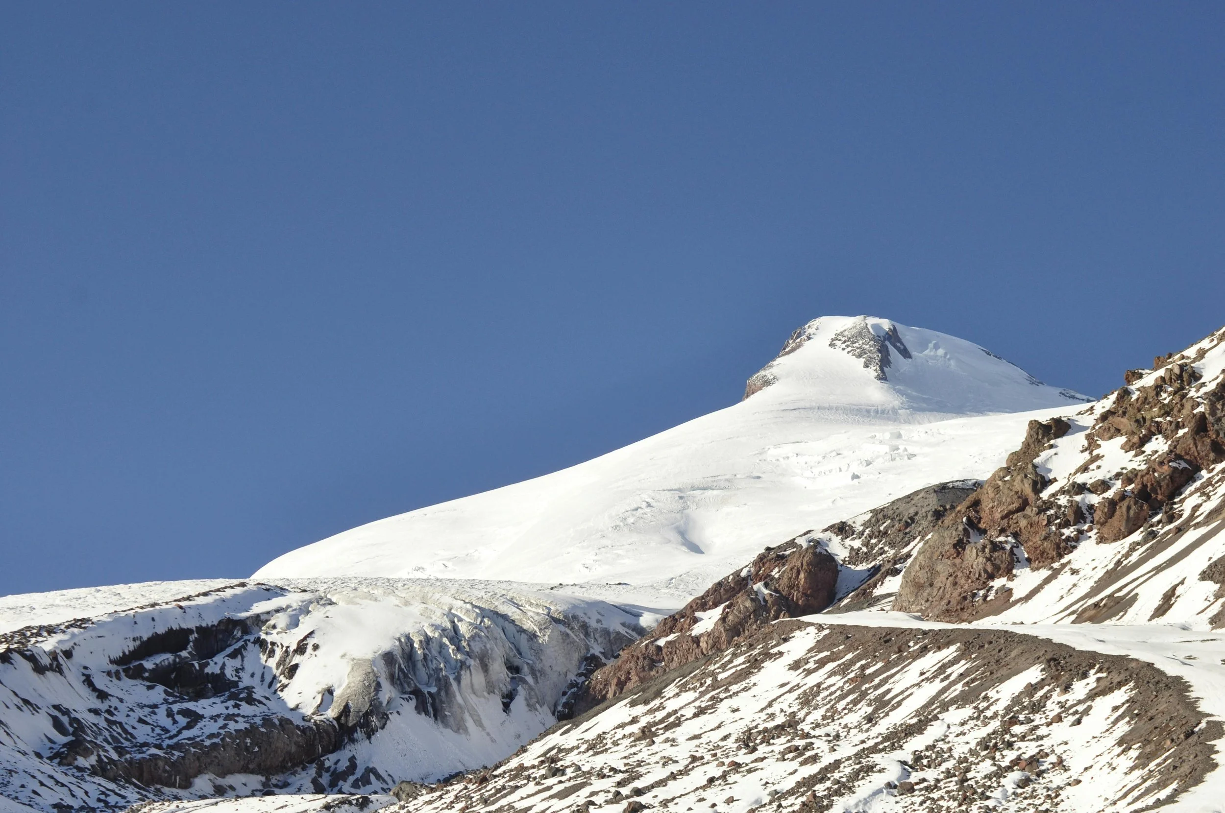 Snow-covered mountain with rocky slopes and a clear blue sky