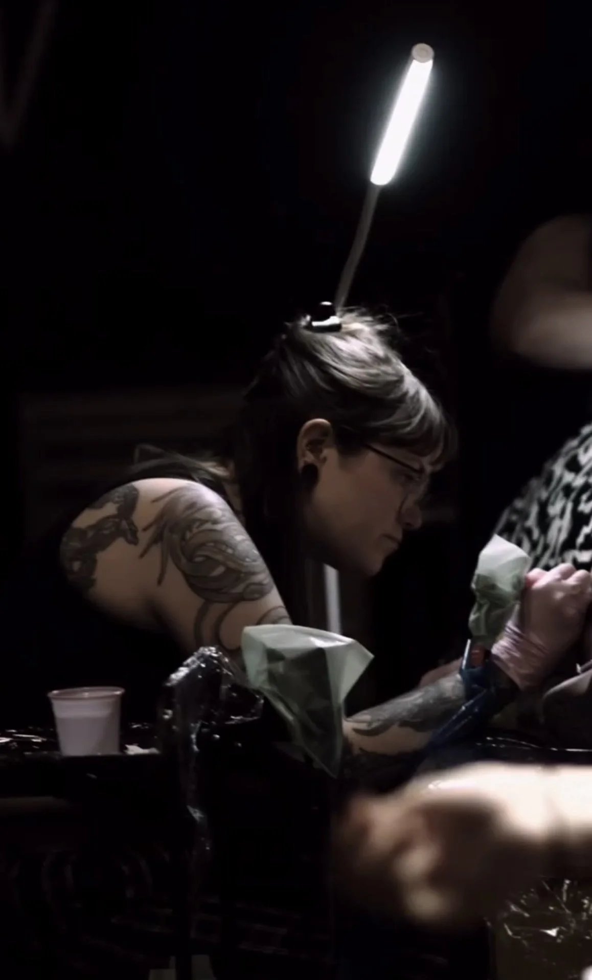 female tattoo artist tattooing colourful flash tattoo on client in liverpool city centre shop