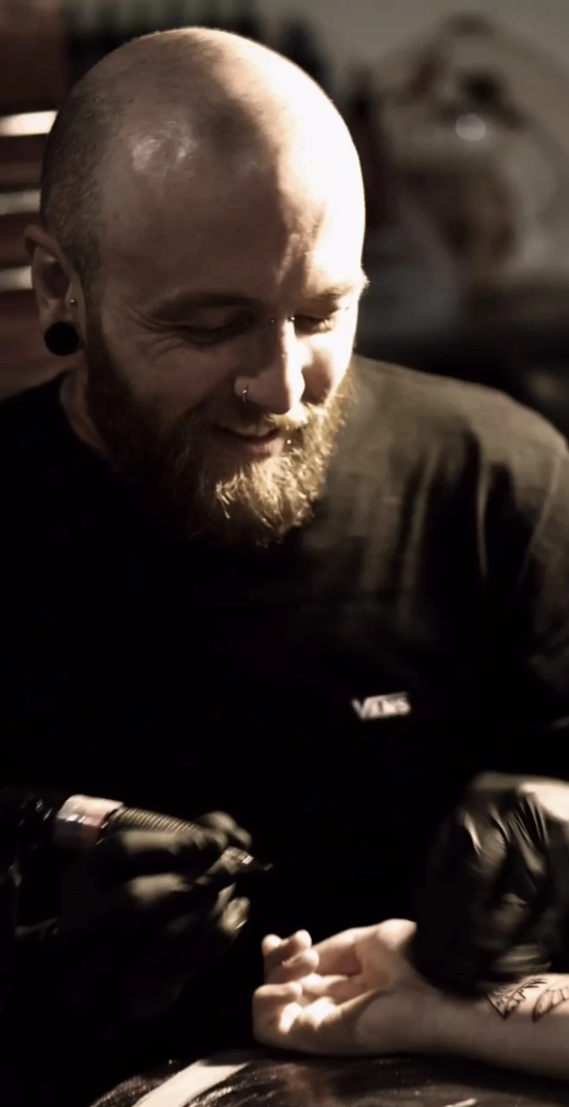 a tattooist from liverpool happily tattooing his relaxed client in clean and professional tattoo studio