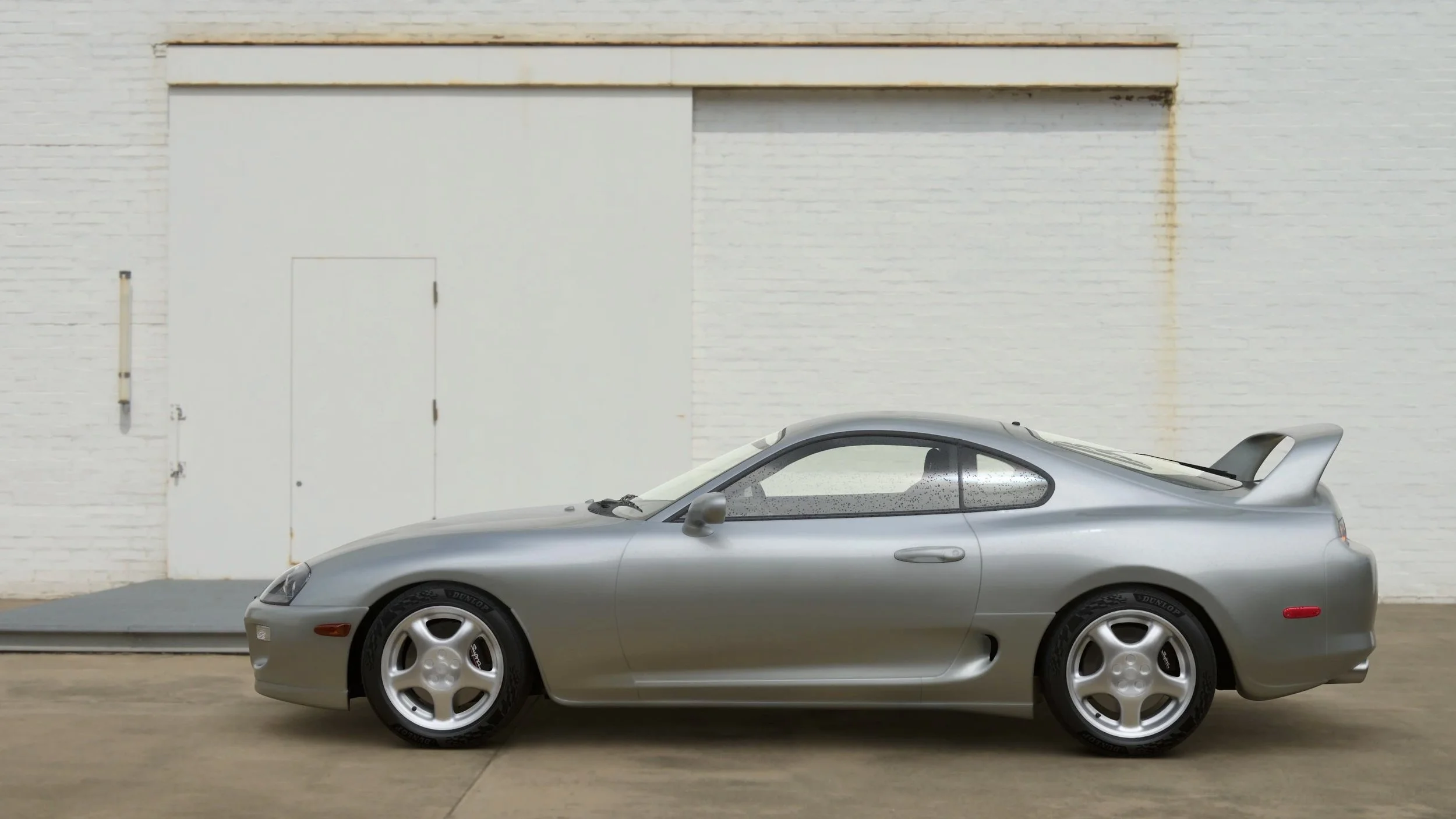 A side profile of a Toyota Supra against a white wall