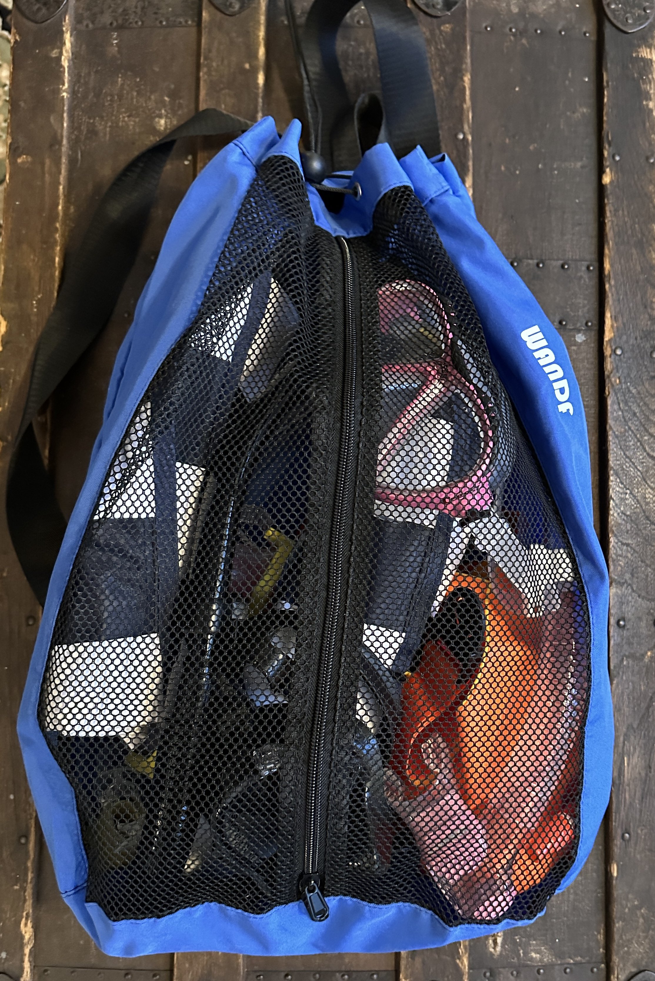 A blue and black Wacom sports bag with mesh side compartments filled with various items including snorkels, floats and diving buoys.