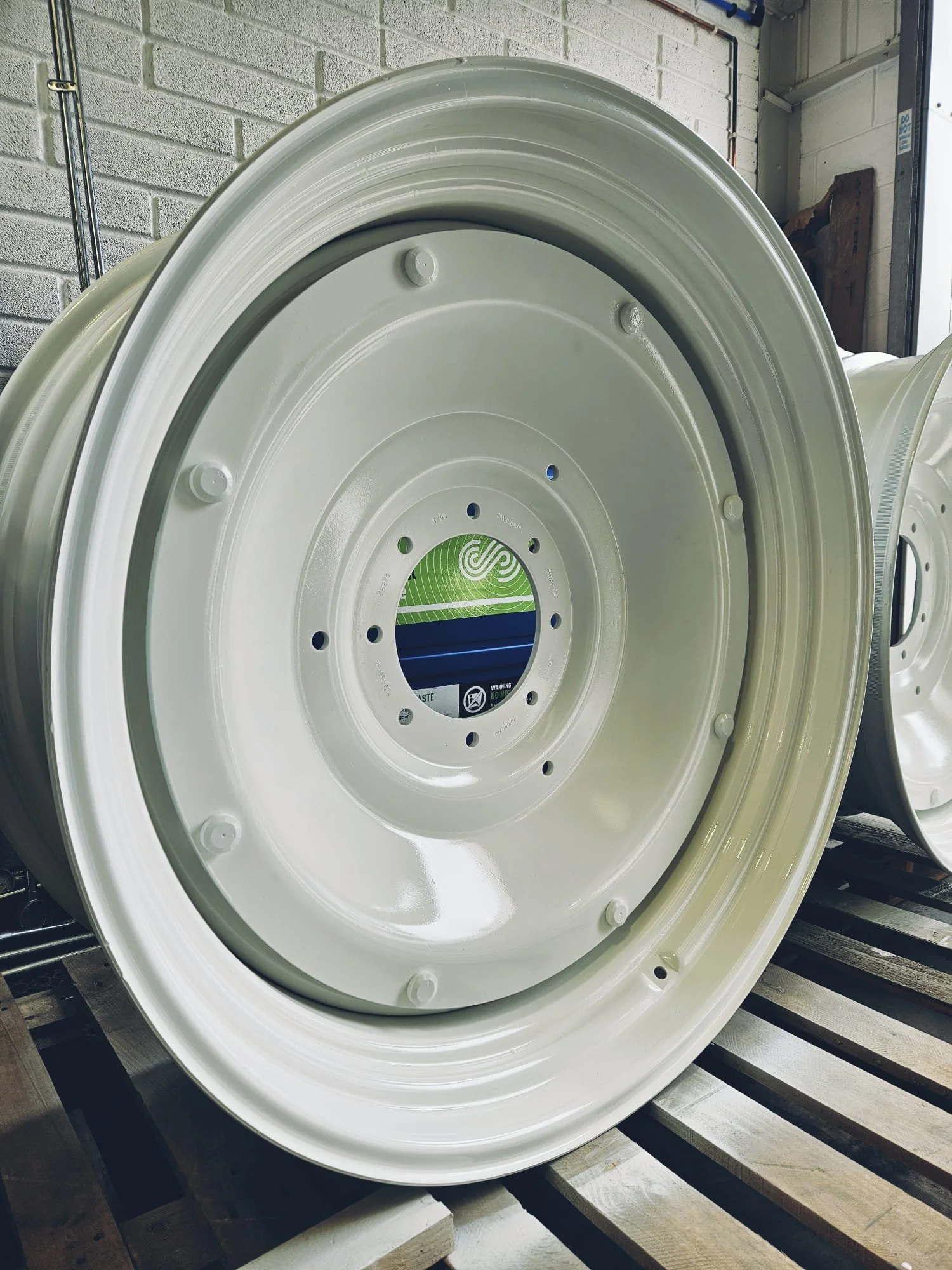 White industrial wheel rim resting on a wooden pallet.