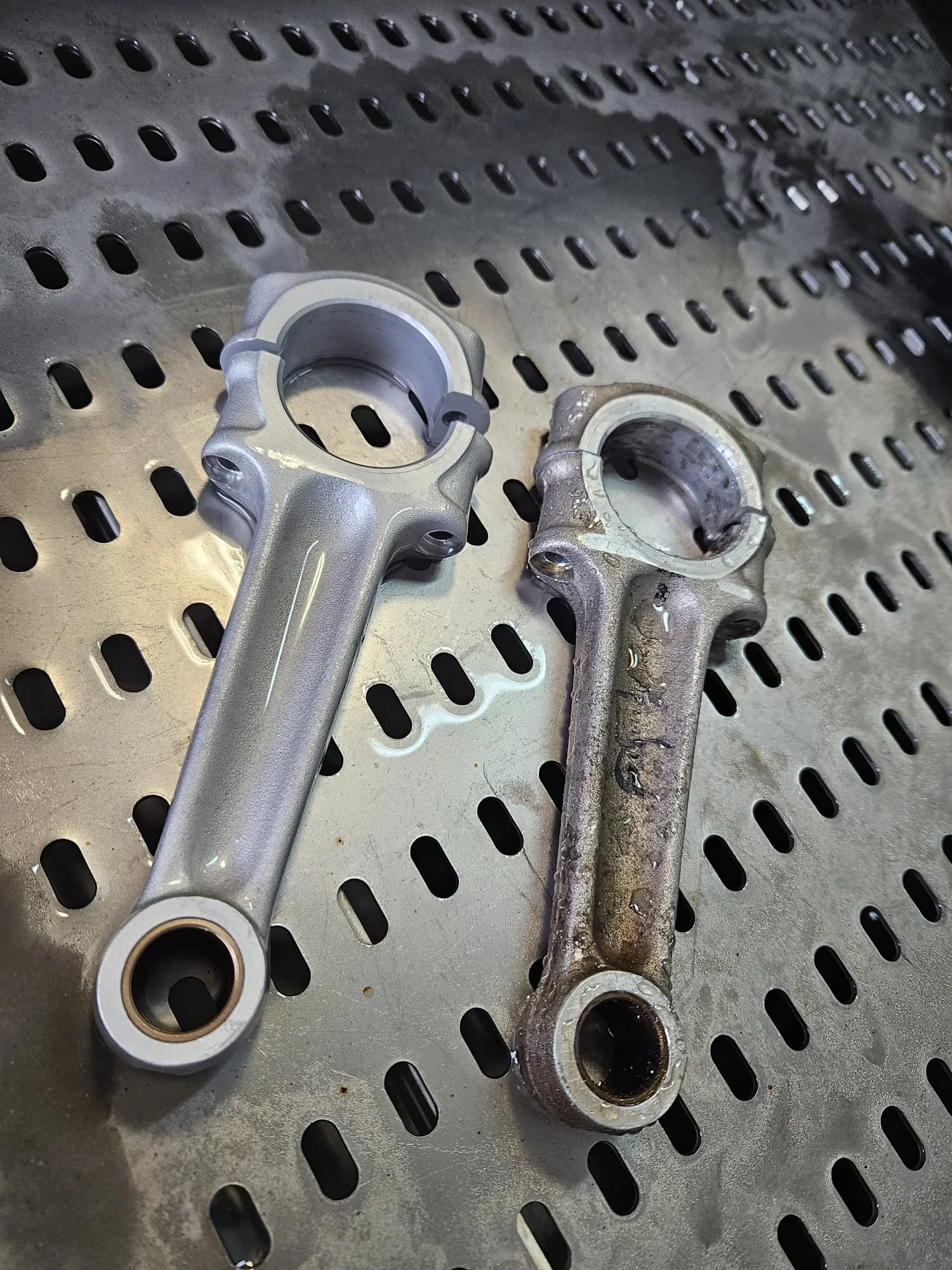 Comparison of a new and used motorcycle steering head bearing. The new bearing is shiny and clean, while the used bearing is dirty and rusted.